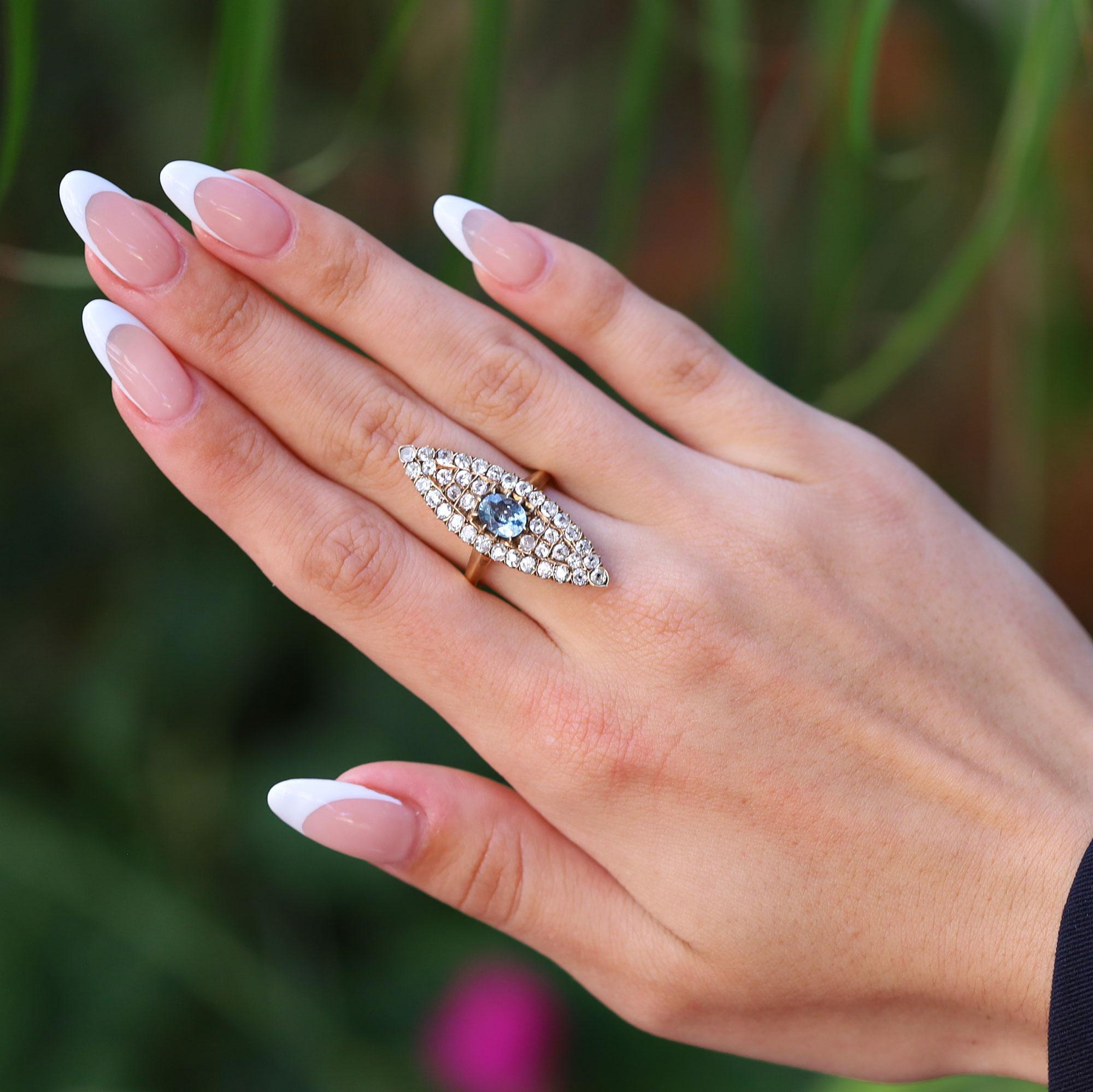 Un vivace anello da cena vittoriano con diamanti e acquamarina, lungo, elegante e sottile. Questo gioiello della fine del XIX secolo è ricco di charme, centrato da una seducente acquamarina e circondato da 40 diamanti antichi taglio miniera. Su