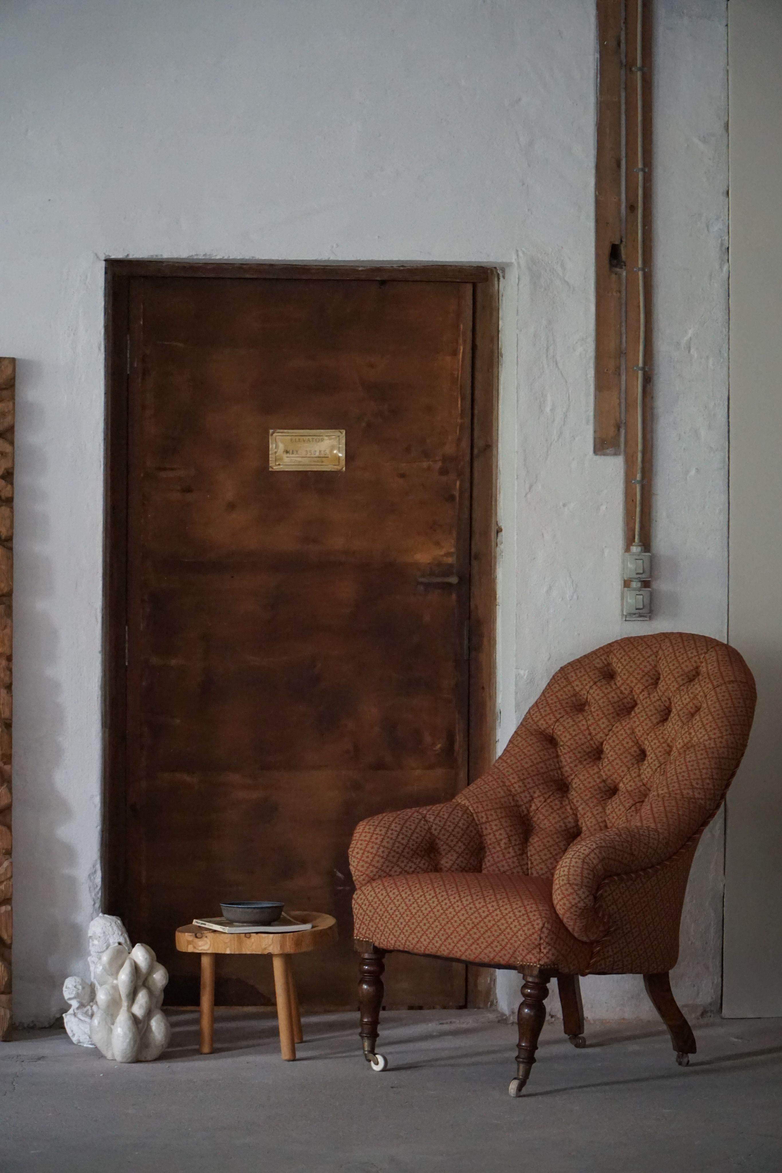 A charming late Victorian mahogany armchair featuring a high, button-tufted back and gracefully scrolled arms.
The fabric is in a tasteful yellow-and-red striped fabric, the chair is further elevated by a rope trim in coordinating orange-red tones