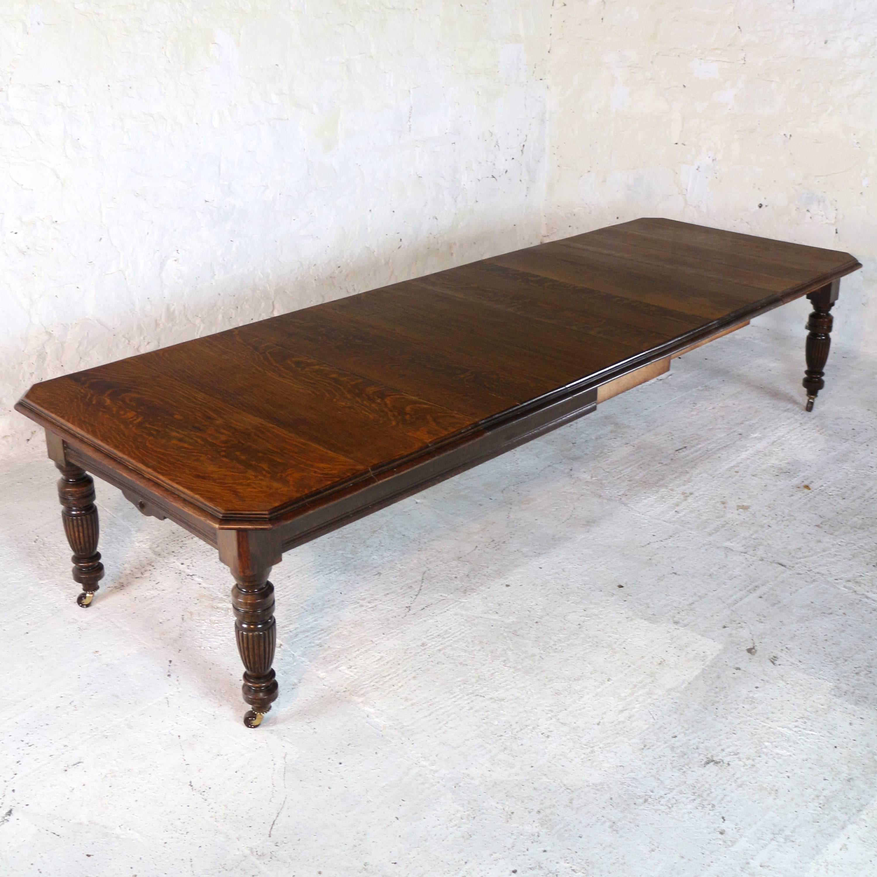 A super late Victorian extending dining table in quarter-sawn oak with four additional leaves and dating to circa 1880. In the Arts & Crafts taste with canted corners to the rectangular top and a moulded edge it stands on four ring-turned and reeded