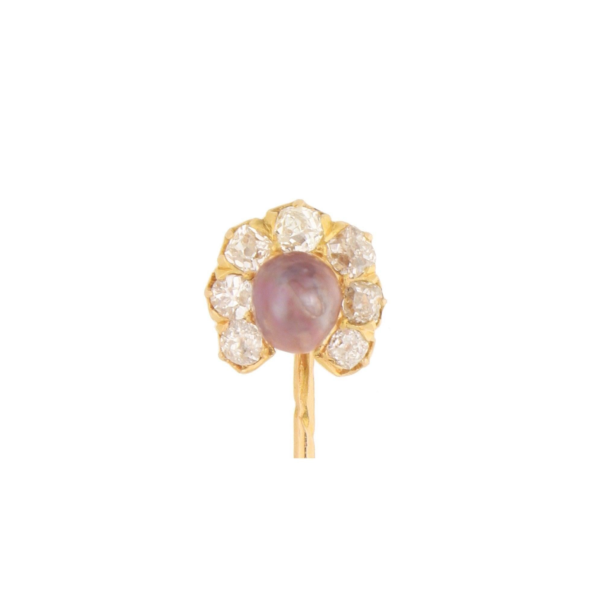 A beautiful Victorian natural pearl and diamond stick pin in 18k yellow gold. The stick pin's head features a natural saltwater off-round pearl of a mesmerising aubergine colour. This is surrounded by a horseshoe motif composed of seven claw-set old