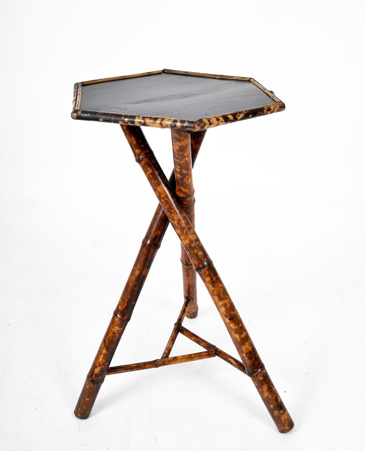 This stunning late 19th Century English three-legged tortoiseshell bamboo side table with stretcher has a hexagonal ebonized top tray edged in bamboo. A versatile piece of antique furniture with a highly desirable vibrant colour to the bamboo and