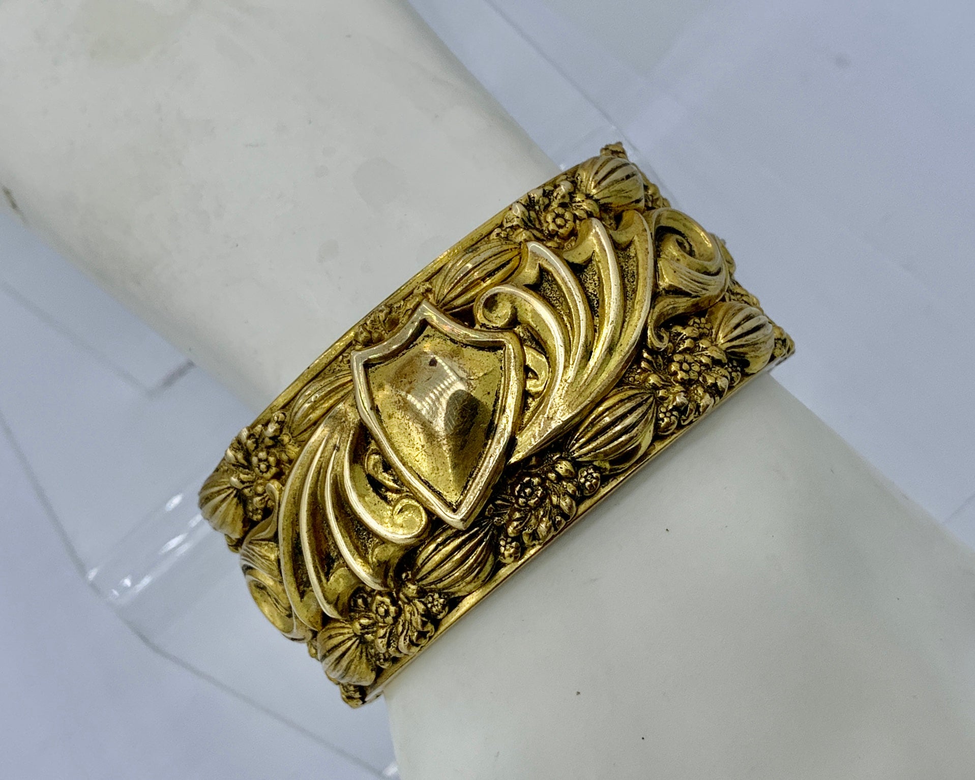 THIS IS A WONDERFUL ANTIQUE VICTORIAN - ART NOUVEAU BANGLE BRACELET IN A STUNNING HEAVY REPOUSSE THREE DIMENSIONAL DESIGN WITH A SHIELD, SCROLLS AND FLOWERS AND LEAVES OF EXQUISITE BEAUTY.  THE BRACELET IS GOLD FILLED AND SUCH A STUNNING EXAMPLE OF