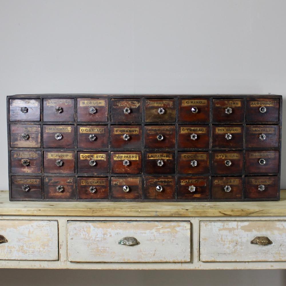A 19th century, wonderfully decorative and useful, bank of chemist or apothecary drawers. Pine painted to simulate faux mahogany with ebonised surround, retaining its original gilt labels, some glass handles later replacements
English, circa 1860.
