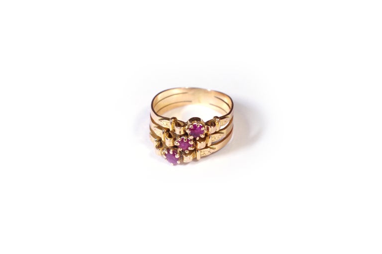 Victorian belt ruby ring in rose gold 18 karats. This small ring is composed of three rings attached together, representing belts with their buckle. Each one is centered with a round ruby which are arranged in staggered and thus form a trio of