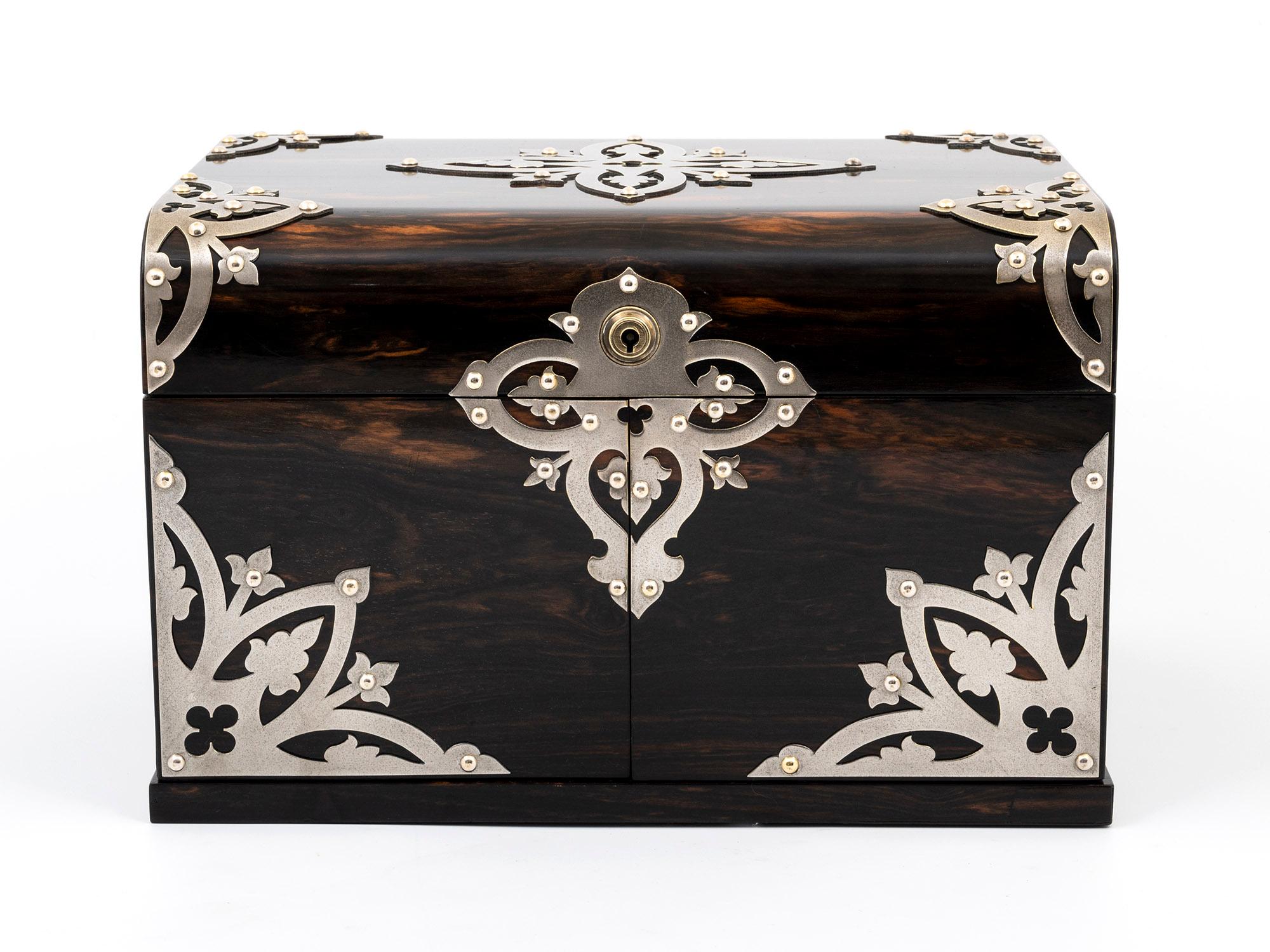 This Jewellery Box is remarkable, a Coromandel & Satinwood lined Jewellery Box by Betjemann.

This dome-top Coromandel Jewellery box features ornate Nickel-plated mounts on the top and front. Featuring a Bramah lock, which, when unlocked, allows