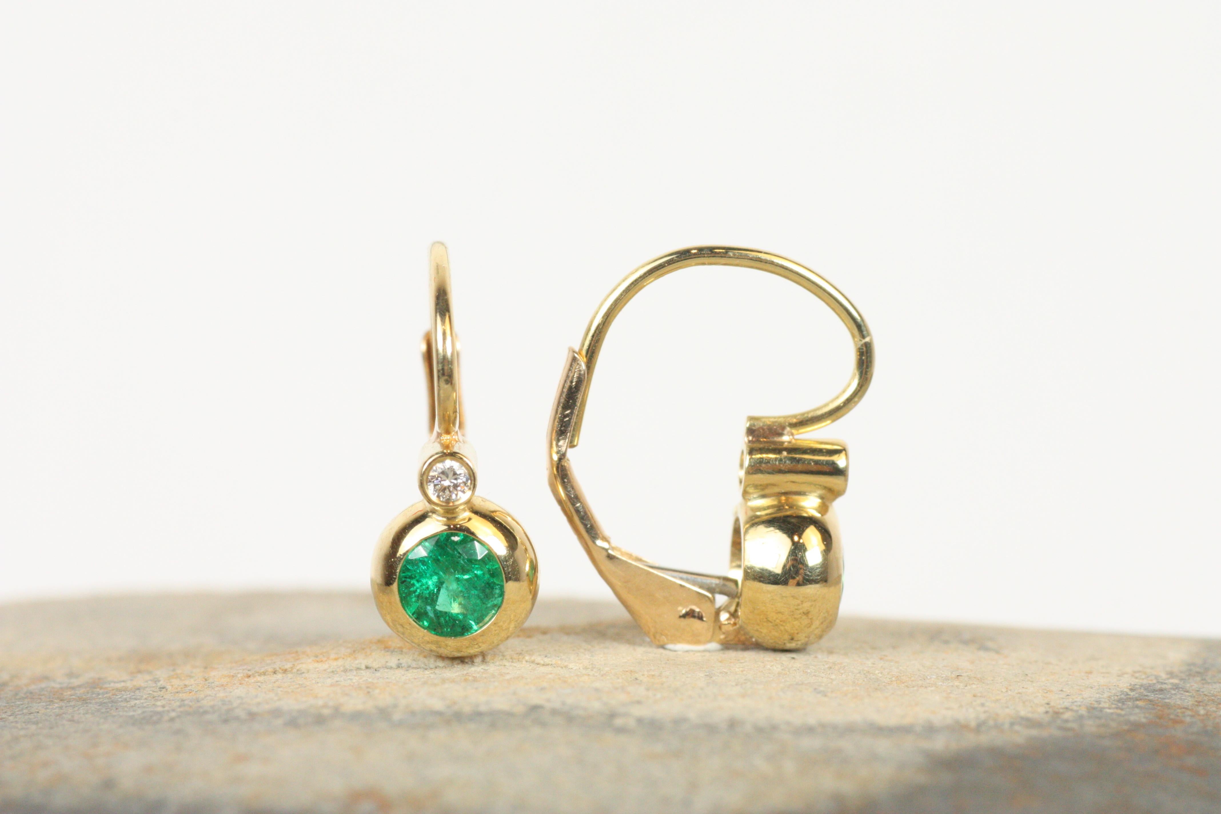 Inspired by Victorian-era elegance, these 18K yellow gold bezel earrings feature stunning emeralds, accented by diamonds. The classic design and timeless materials make these earrings a luxurious addition to any collection, perfect for both formal
