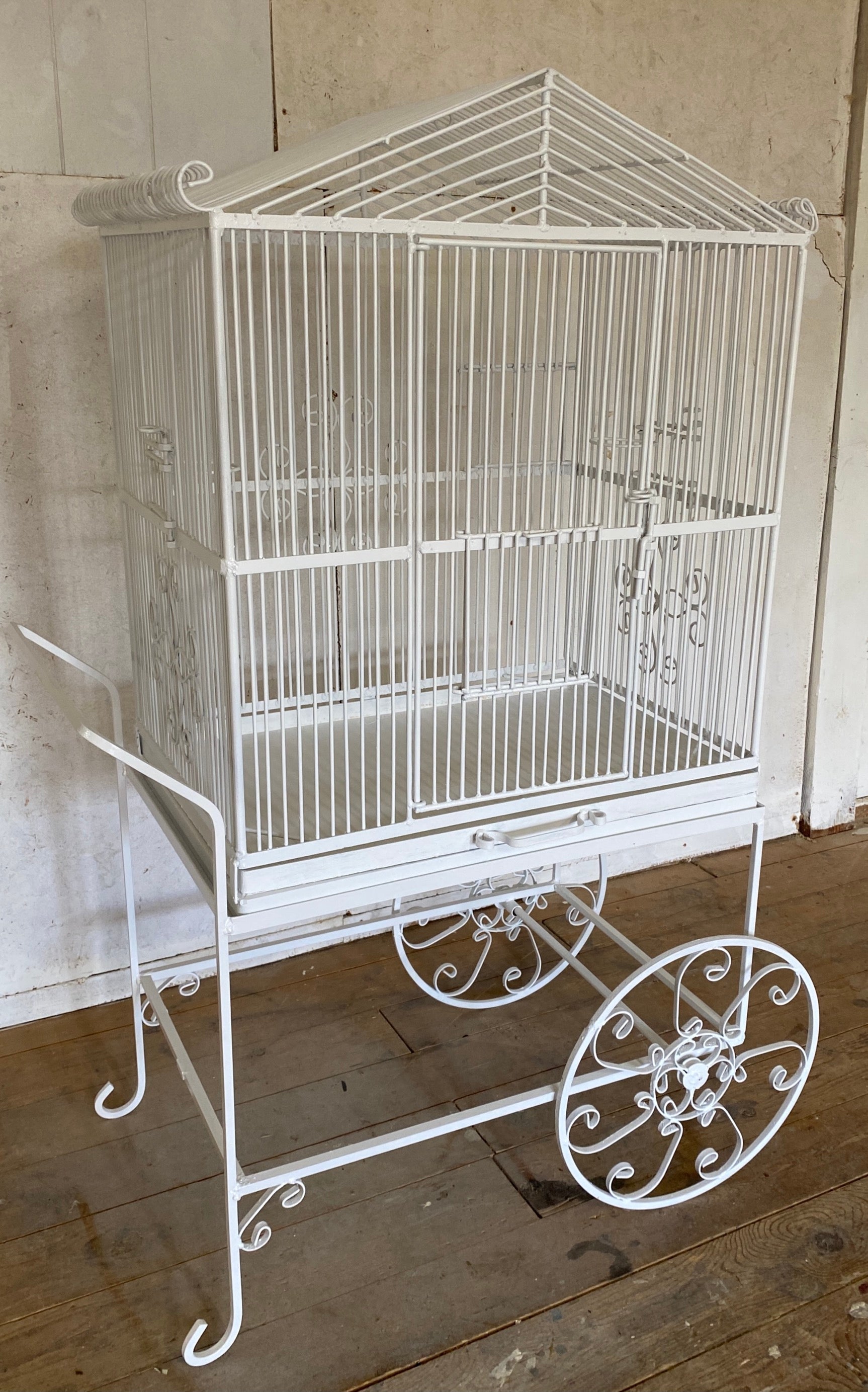 A large English Regency style white painted wired bird cage sits on top of a rolling cart that is both decorative and also handy to move for cleaning or give your aviary friends a new vista. 

Cart 21.5 d x 26 w x 30