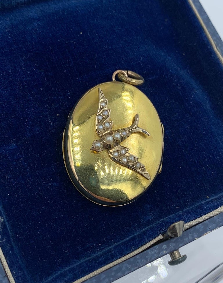 This is a gorgeous antique Victorian bird swallow locket pendant in 14 Karat Gold adorned with pearls in an extraordinary three-dimensional design.  The locket is one of the most beautiful antique animal motif lockets we have seen.  The locket is a