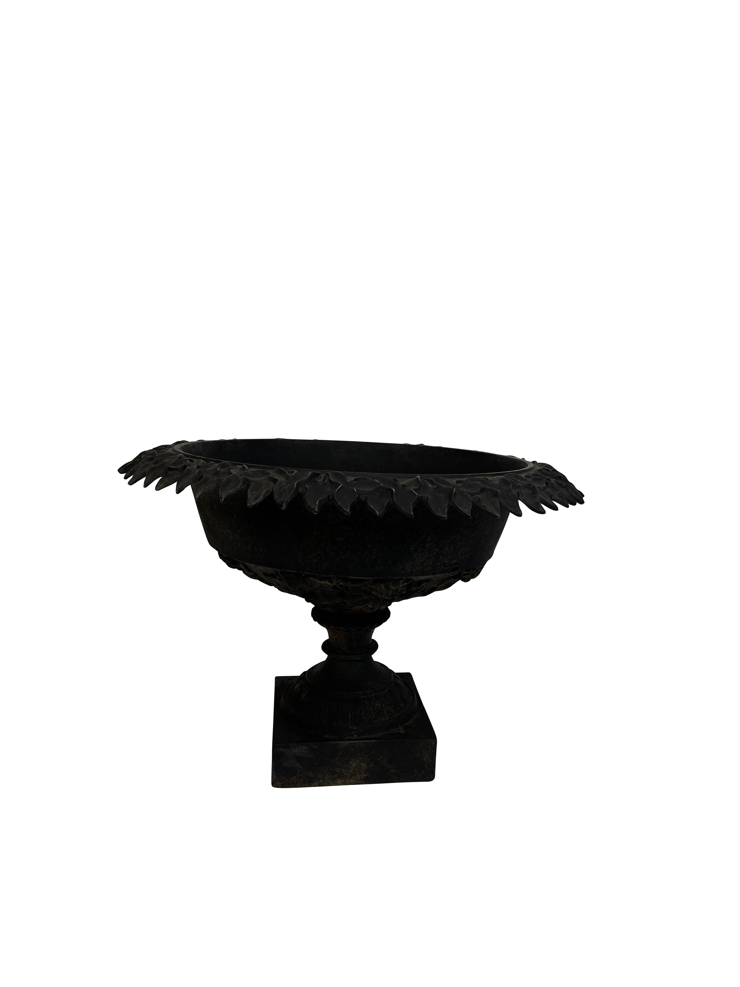 Victorian black cast iron round urn form jardinière/ planter. Pedestal base with leaf form decoration and flower petal decoration around the rim, a hole in the bottom for drainage. The basin sits on a square base. Black matte finish beautiful indoor