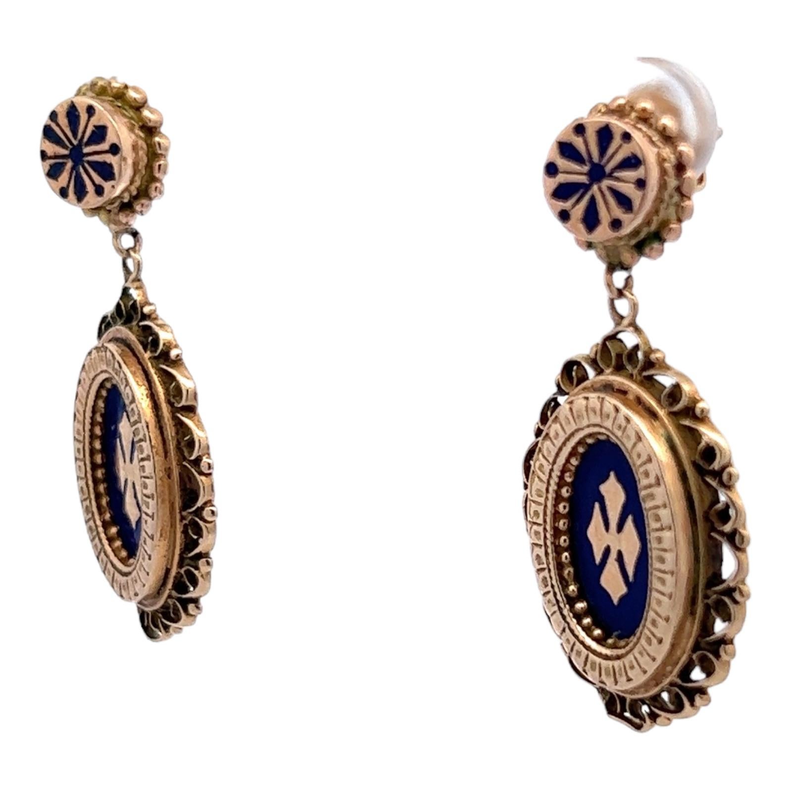 Original Victorian earrings crafted in 14 karat yellow gold. The earrings feature black enamel accents, oval drops handcrafted in burnished yellow gold. The earrings measure 1.50 inches in length and .75 inches in width. 