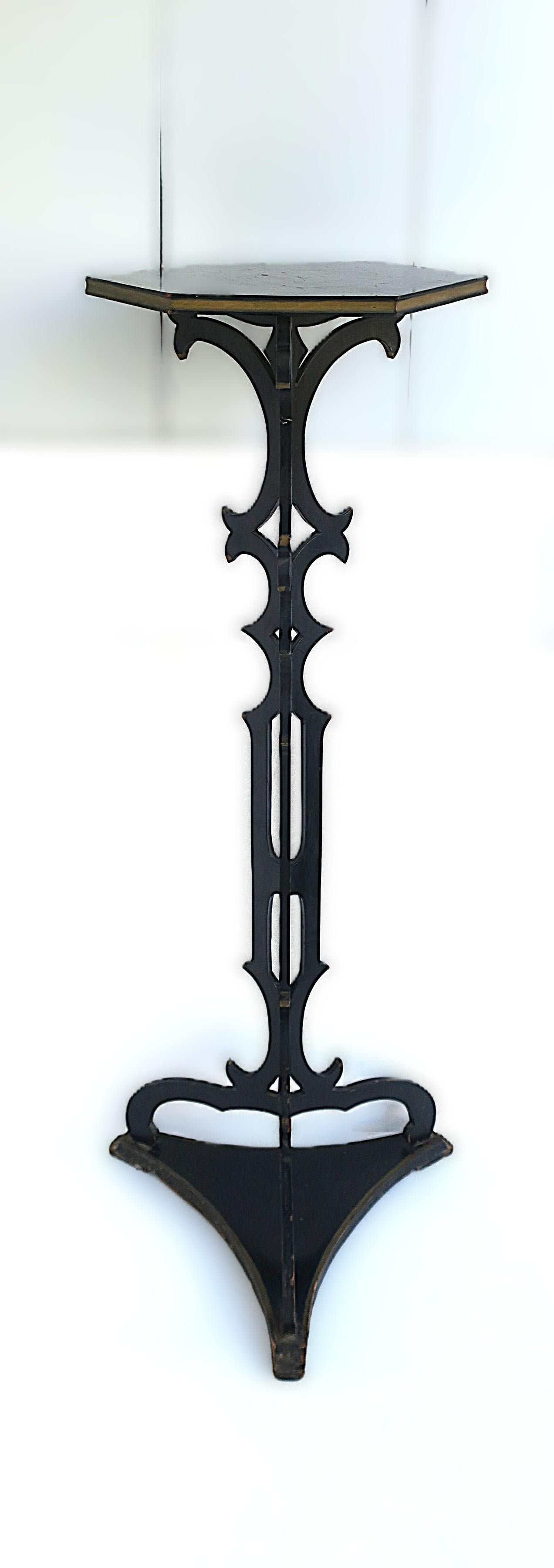 A column wood pedestal plant stand finished in a black lacquer with gold accents, Victorian design period, circa late-19th century to early-20th century. Top has a hexagon shape with gold detail around. Center 'pillar' area has a pierced cutout