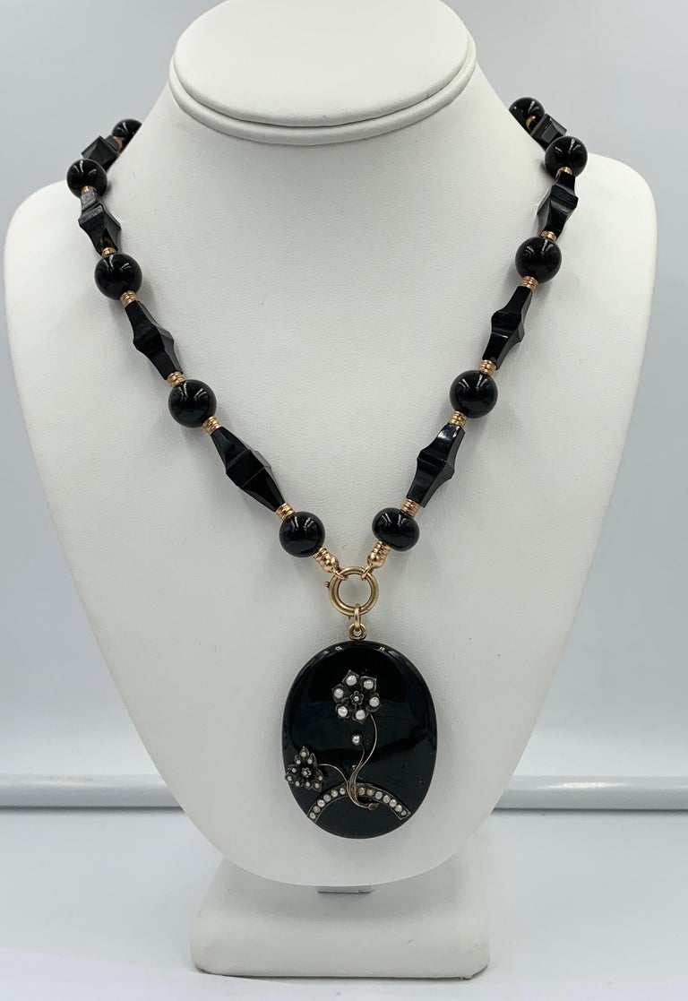 A magnificent Victorian - Belle Epoque Picture locket pendant necklace in Black Onyx, and 14 Karat Gold with Pearl adornments in a flower motif design.  This is one of the most stunning and impressive locket necklaces we have seen.  It is so rare to