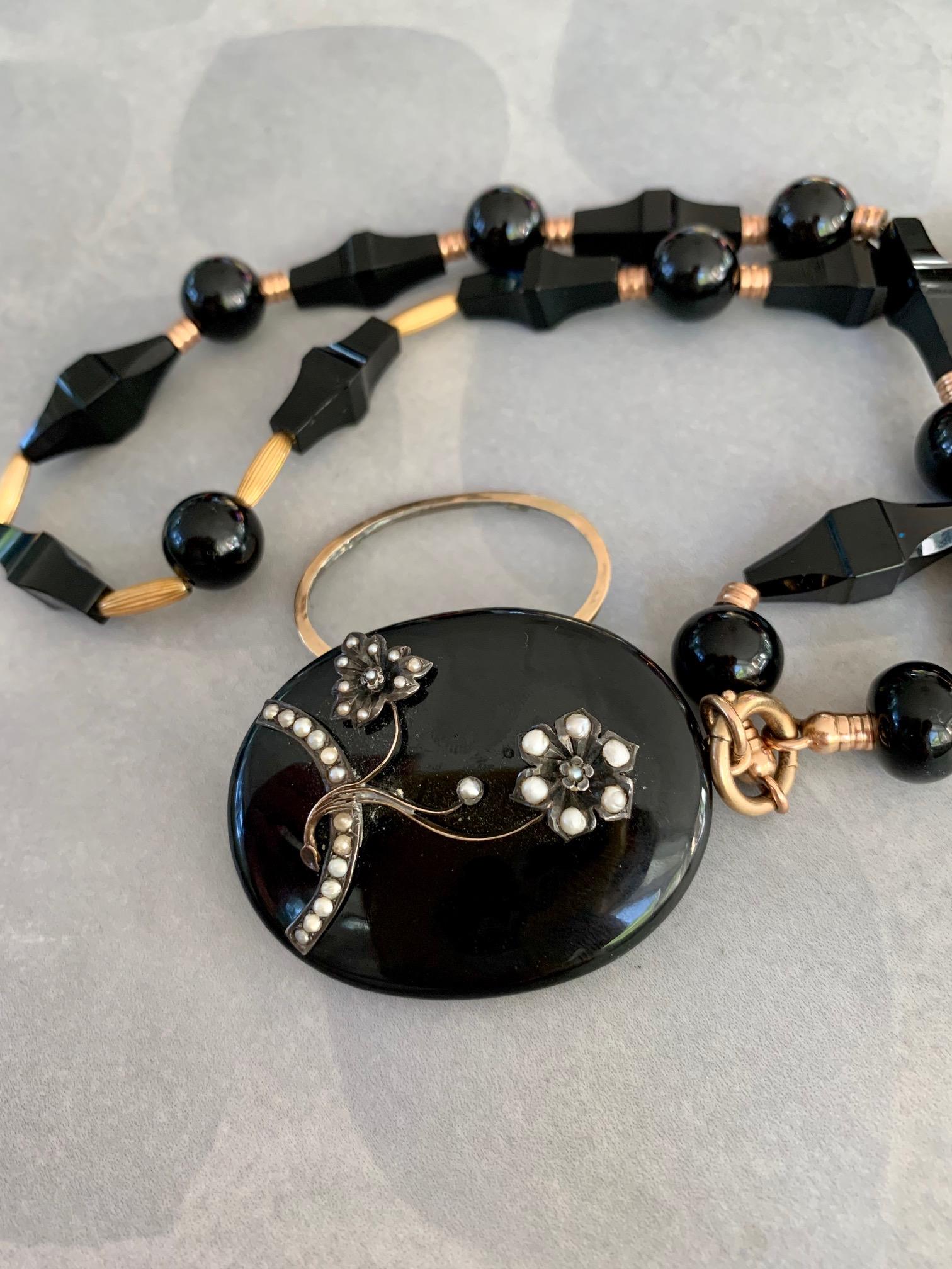 This stunning mourning locket and necklace are made with black Onyx as the featured stone.  It has been accented with seed Pearls on the front of the locket. The necklace features black Onyx beads of various shapes which are alternated with Gold