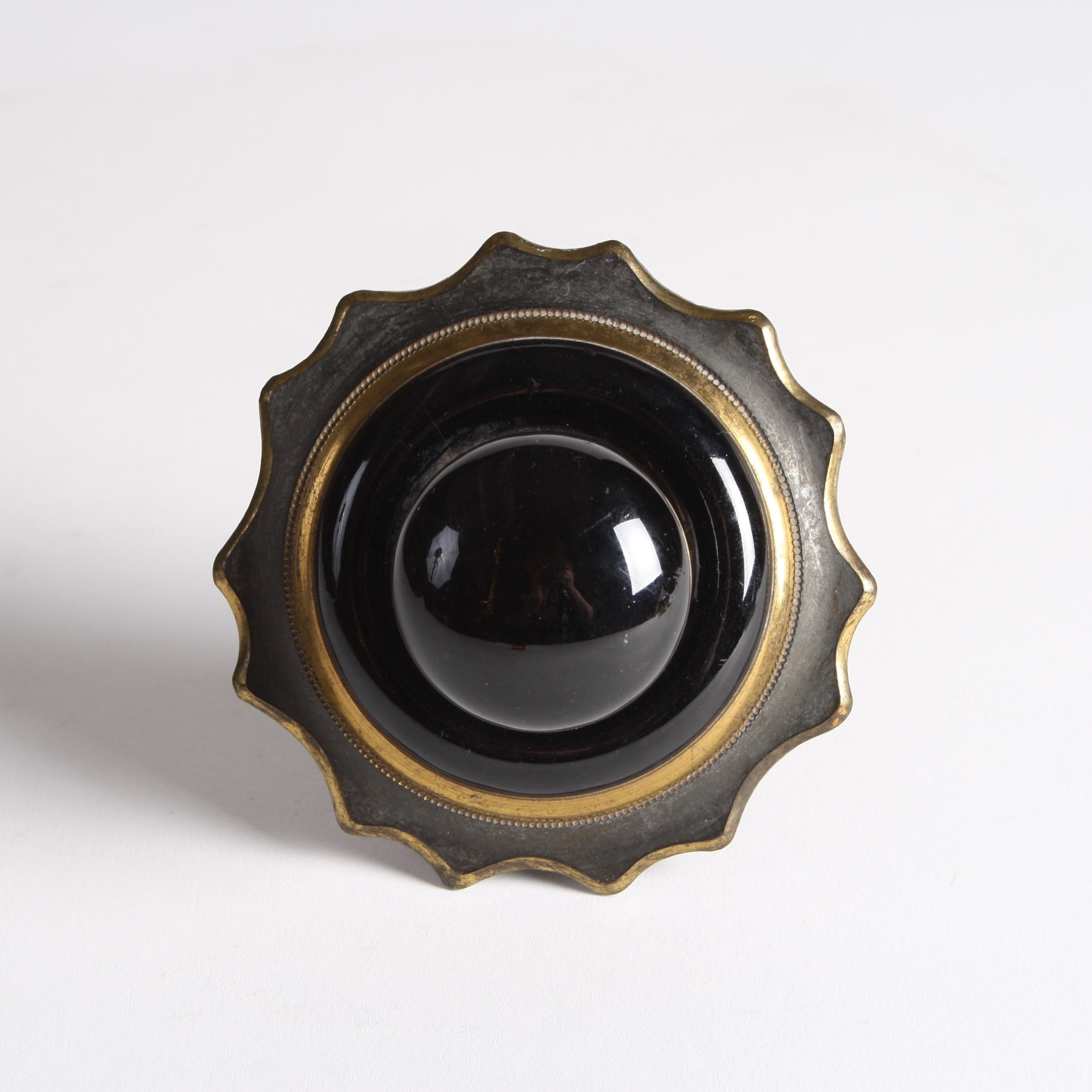 A Victorian black ceramic and two-tone brass bell pull, back-plate with scalloped edge.

With original chain mechanism for linking to bell.

Back-plate diameter: 3 3/4 inches.

           