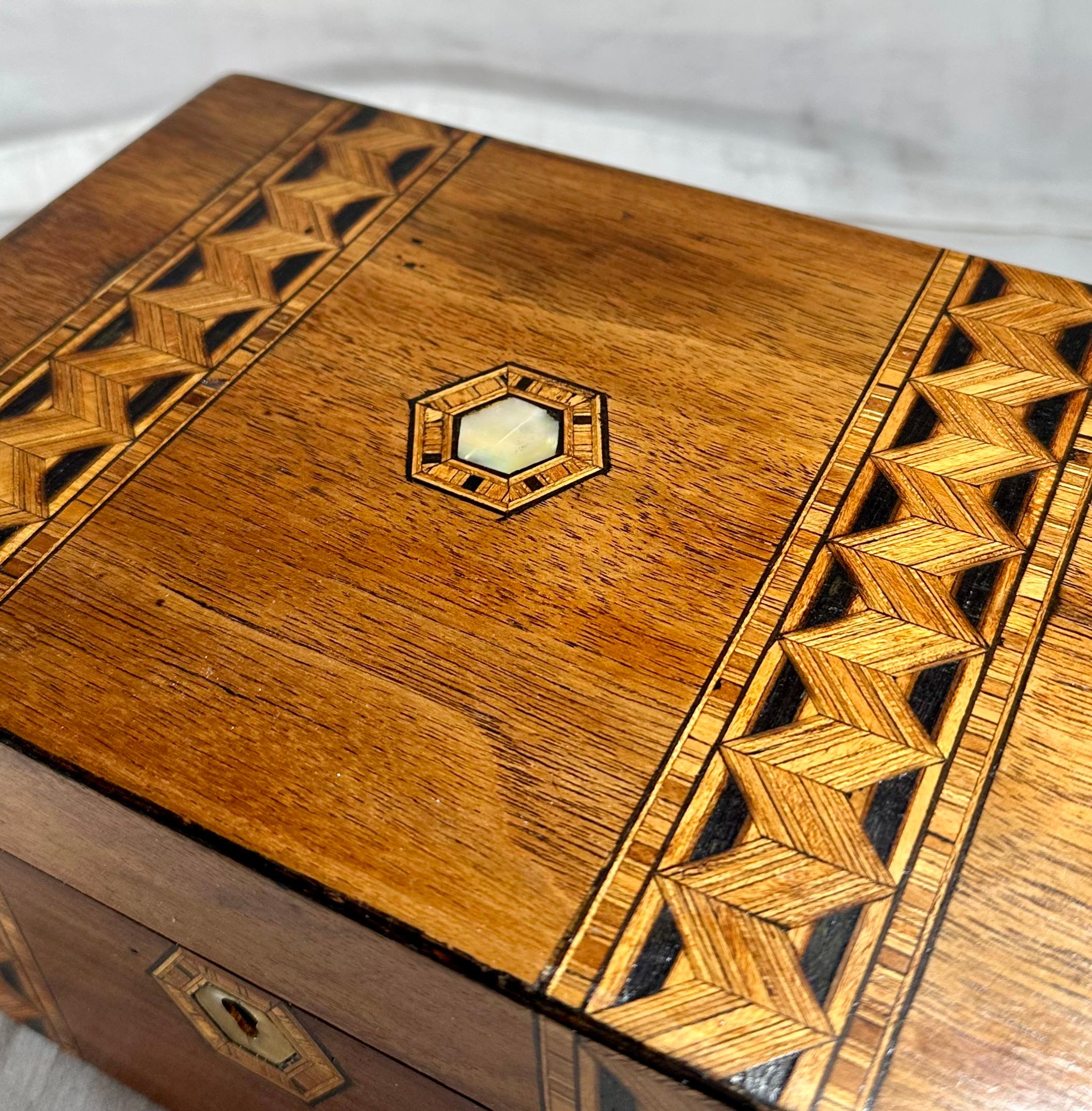Caja de té victoriana de nogal negro Tunbridge Ware, circa 1880. 

Preciosos y exclusivos adornos de bandas con diseño de mosaico de incrustaciones geométricas, con llave de madreperla y medallón superior.  Caja de madera patinada y brillante con