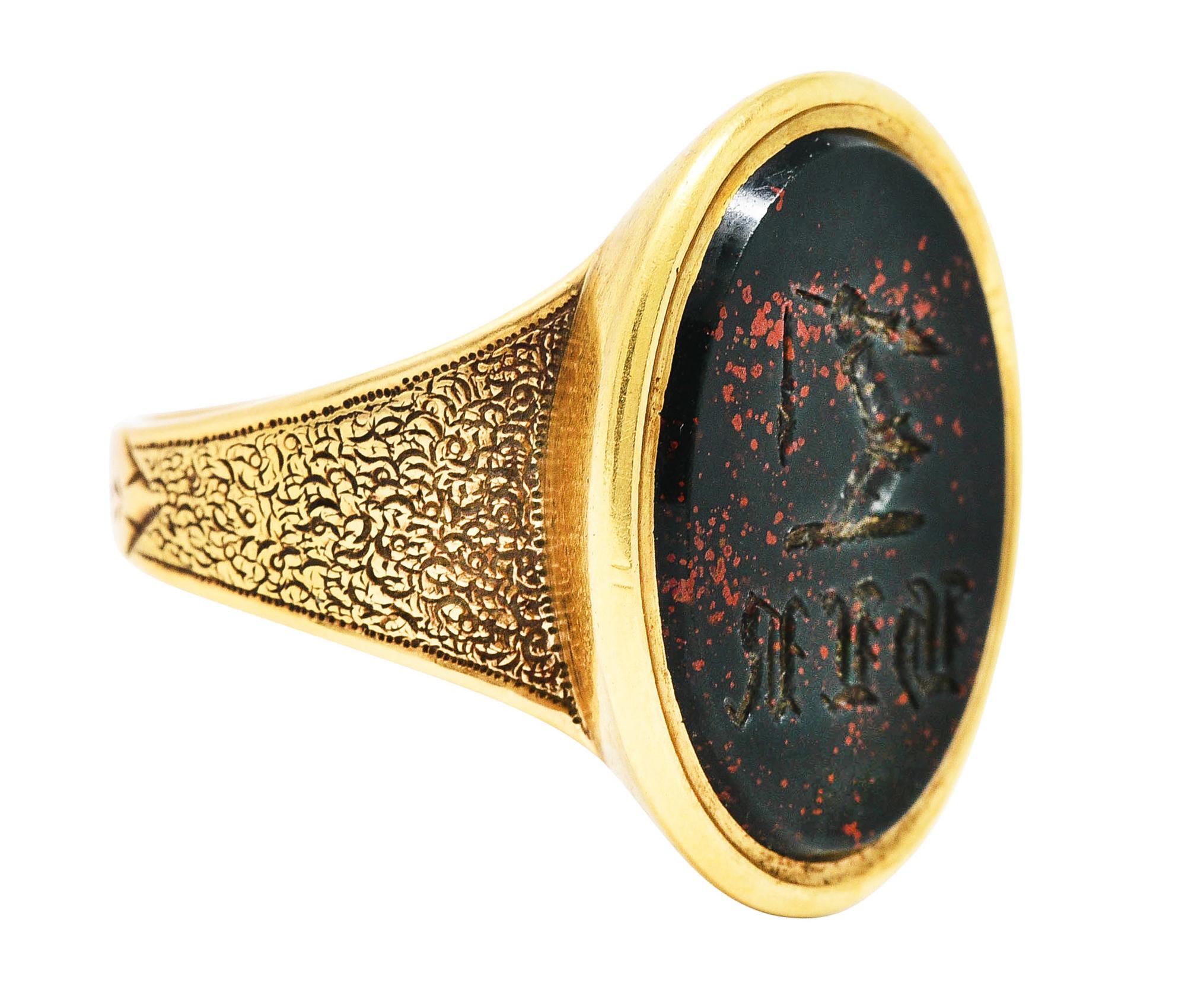 Signet style ring designed with oval face and stylized shoulders

Centering a bloodstone slab measuring 20.5 x 15.5 mm

Bloodstone is opaque bluish green with strong red mottling

Signet features intaglio of armored hand holding broken spear with