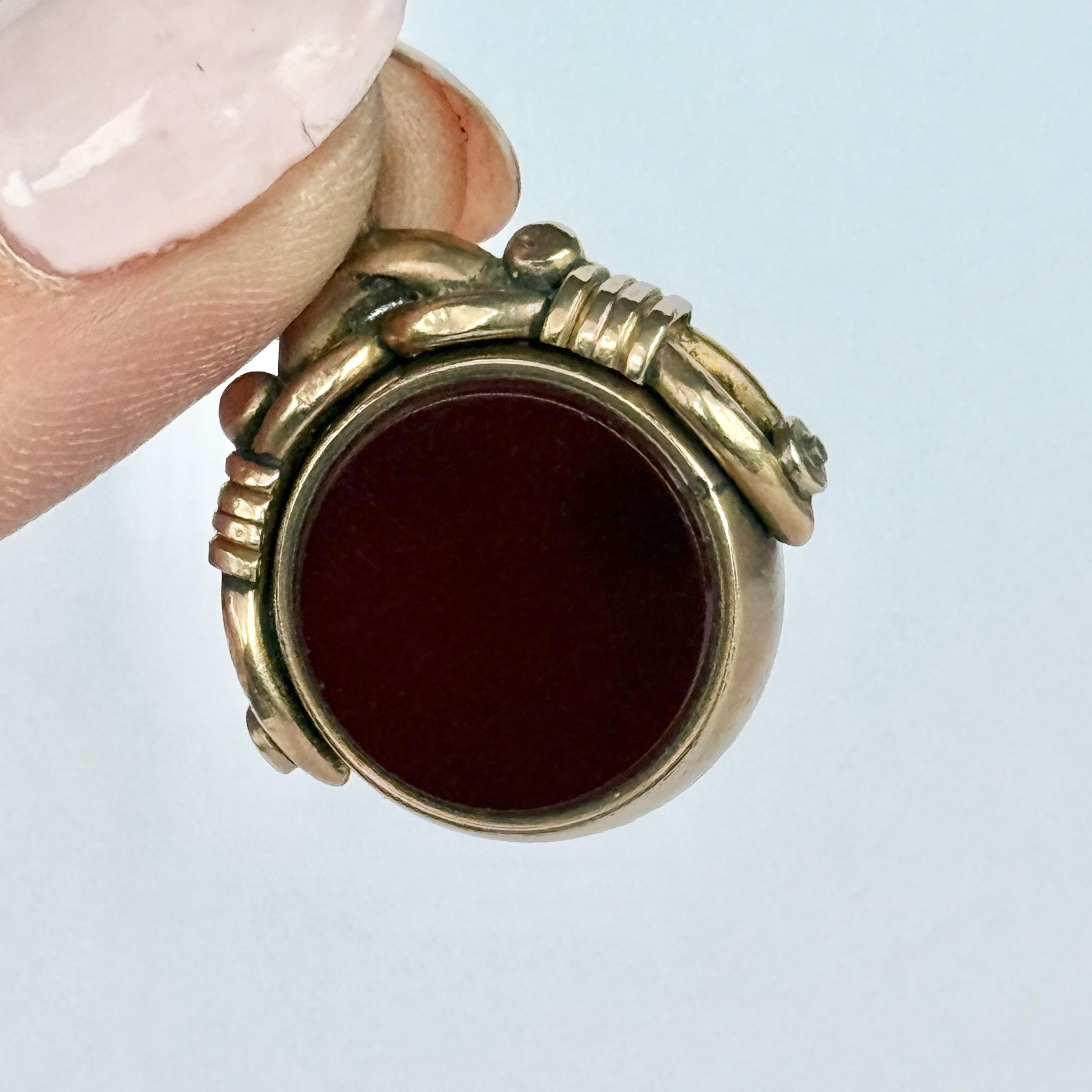 This classic 9ct gold fob holds a carnelian and bloodstone that spin! The gold work above the stones are ornate. 

Stone Diameter: 16mm
Height From Loop: 28mm

Weight: 7.3g


