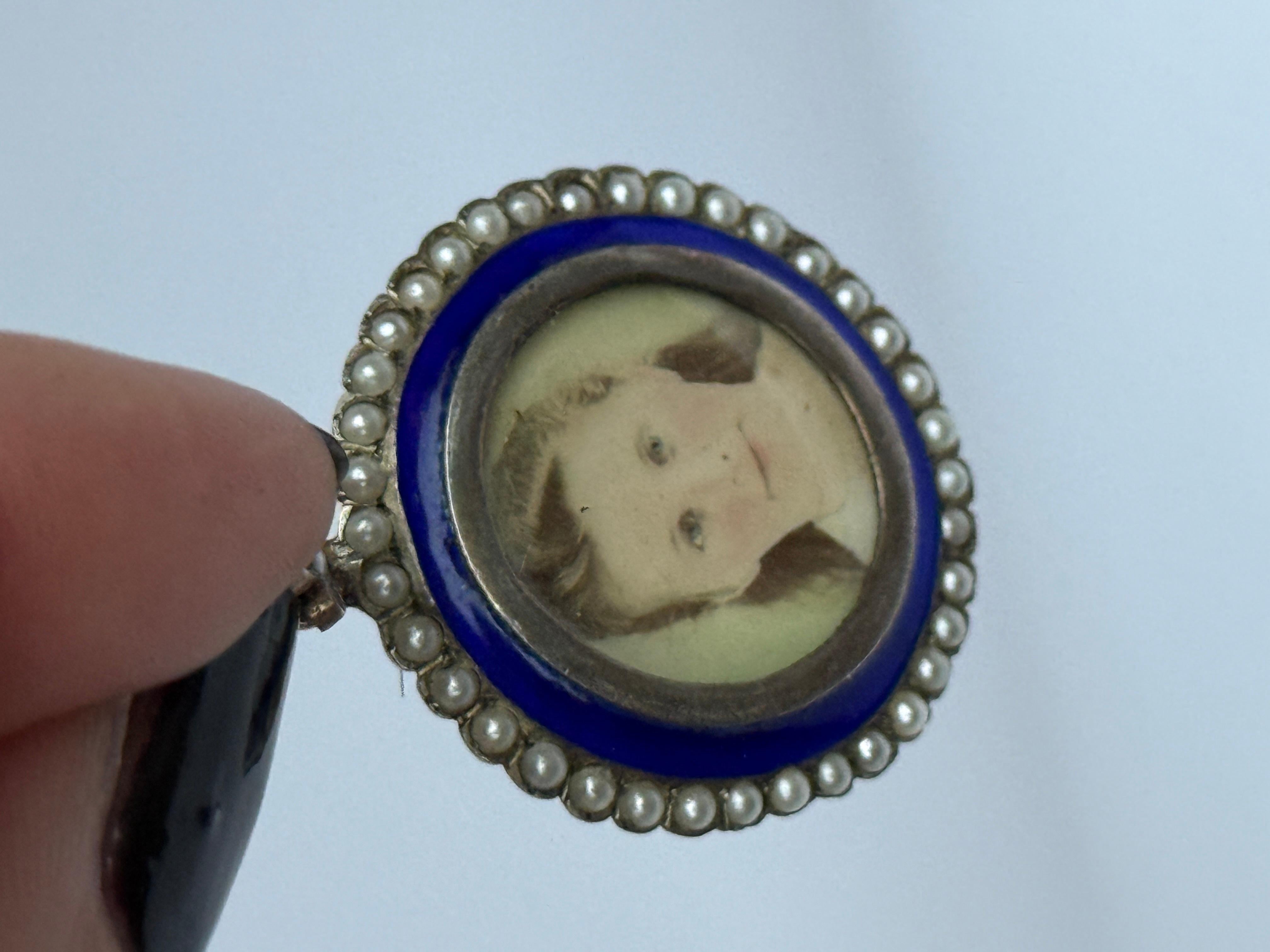 Lo smalto di questo ciondolo è di un blu stupendo. La parte anteriore contiene un ritratto circondato da una cornice d'oro e da uno smalto a macchie, rifinito con un'aureola di perle. Il retro del medaglione è dotato di uno scomparto in vetro