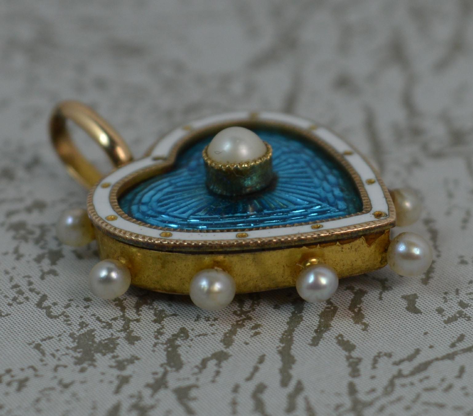 A stunning Victorian period locket pendant. Amazing romantic heart shape.
Modelled in yellow gold with a glass locket compartment to reverse.
The front designed with a pearl set to centre of a very bright vivid blue enamel with white enamel to the