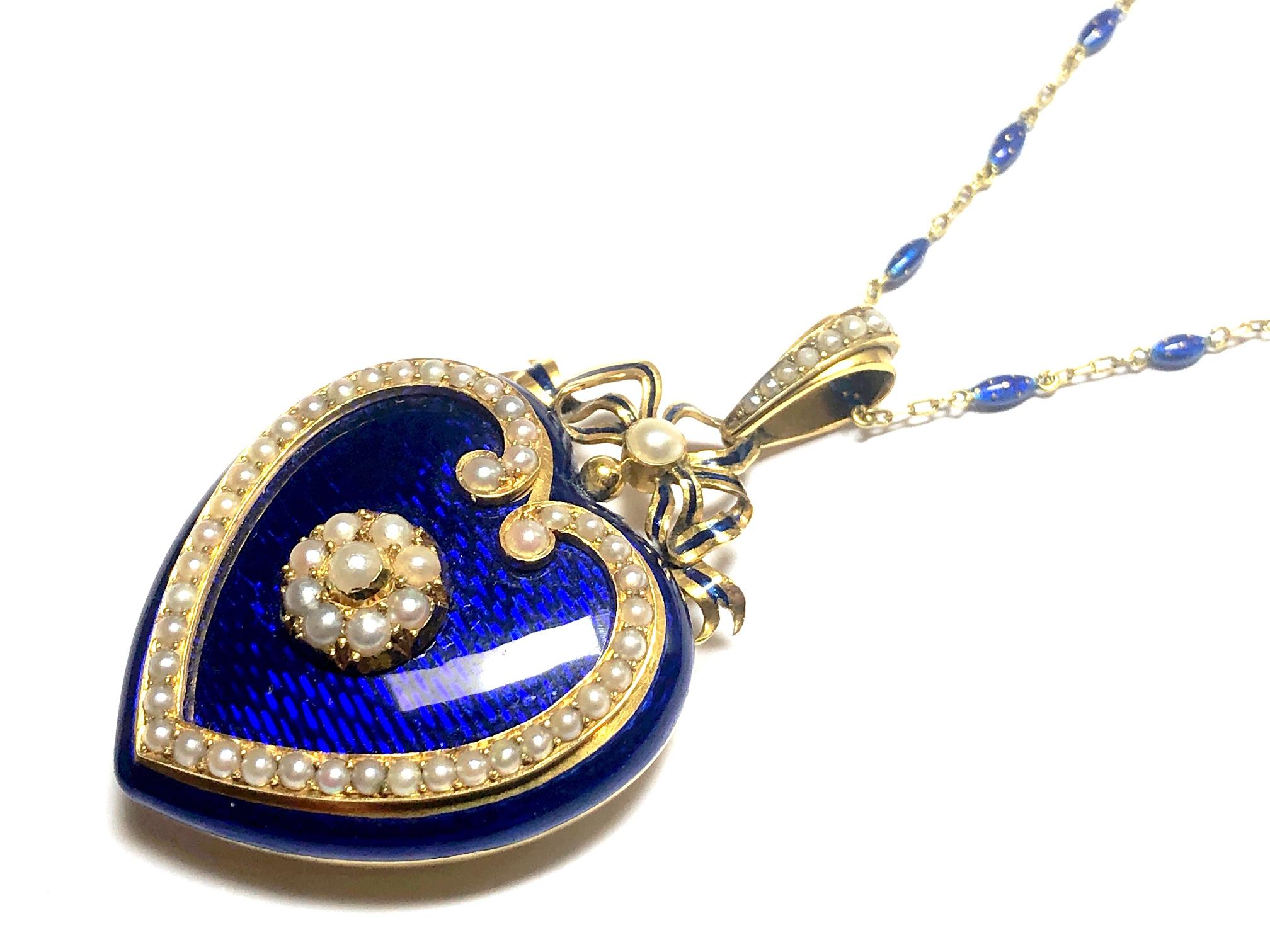 A Victorian, blue enamel heart locket, with a central cluster and heart shape surround set with natural half seed pearls, on a background of blue, guilloche enamel, with a picture locket at the back. The heart is surmounted by an enamelled bow, set