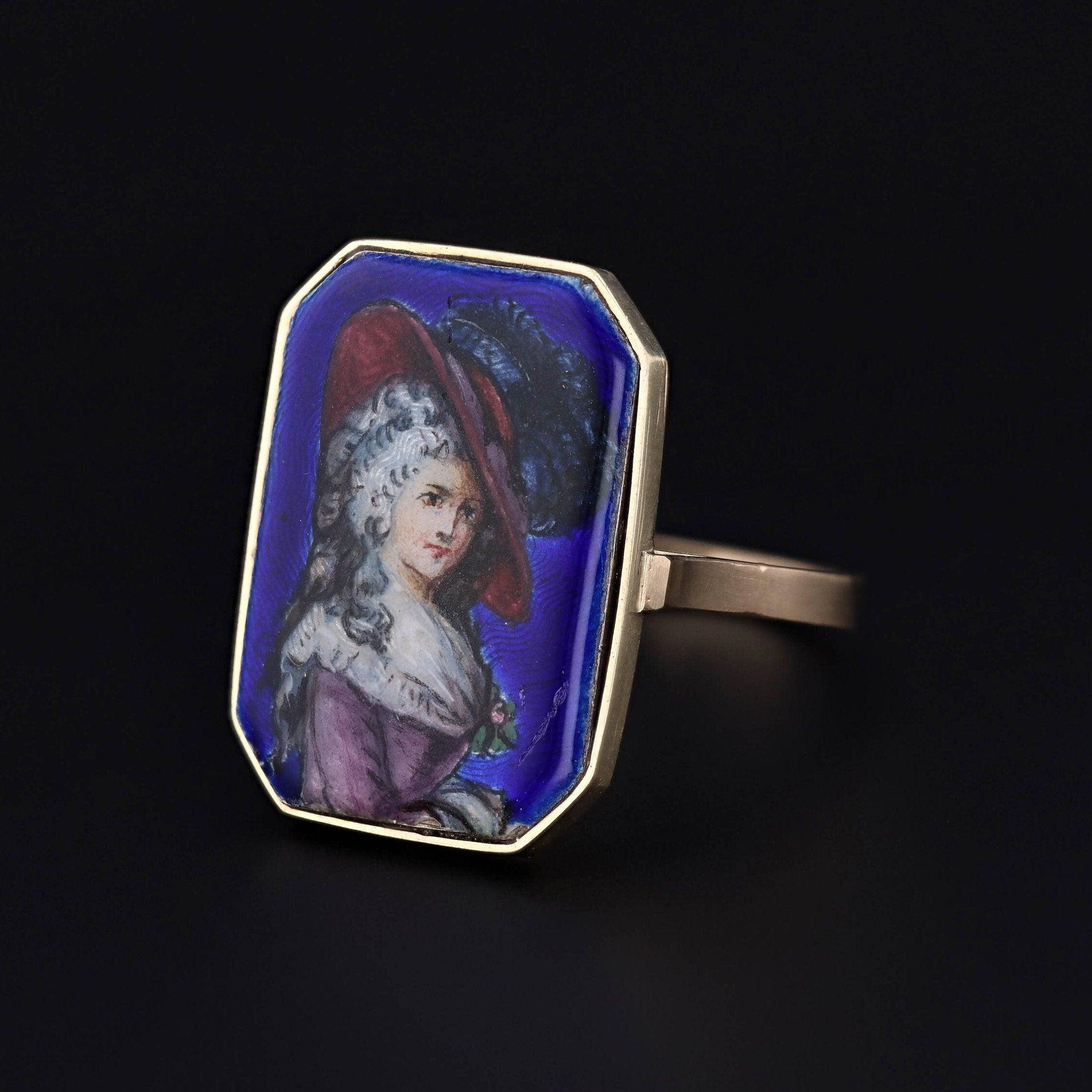 Questo anello è stato convertito da una spilla antica (circa 1880) rimuovendo il gambo della spilla e aggiungendo una montatura in oro 14k. Il pezzo in smalto raffigura una donna del XVIII secolo finemente vestita con dettagli delicati.

La faccia