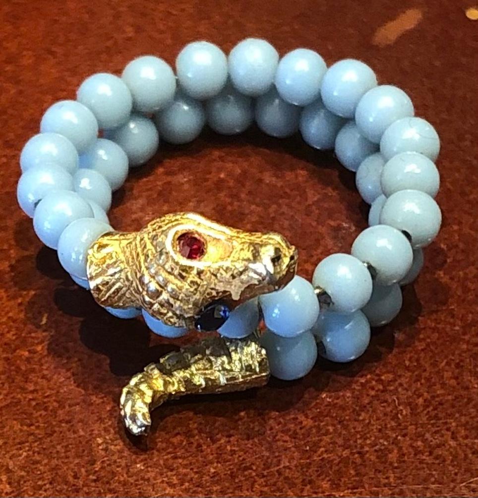 9ct gold Victorian snake ring  consisting of 37 tiny blue glass beads threaded on flexible gold wire between a gold tail and a smiling snake head with  a sapphire and ruby eye.   Since ancient times snakes have been seen as a symbol for “Eternal