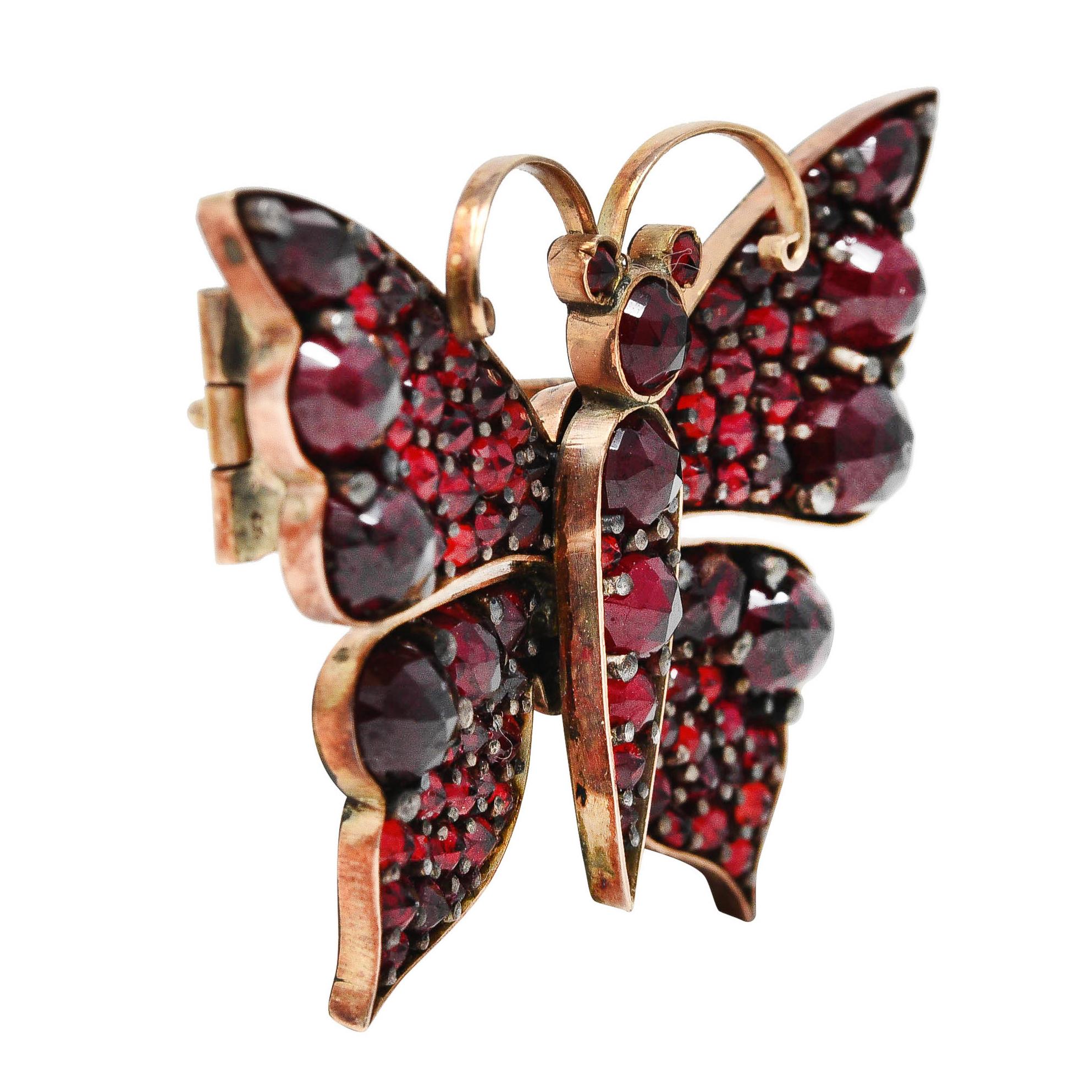Brooch is designed as a stylized butterfly topped by scrolled wire antennae. With faceted Bohemian garnets throughout - bead set by silver. Measuring from 4.0 mm to 1.5 mm. Very well matched in medium dark red color. Completed by a pin stem with