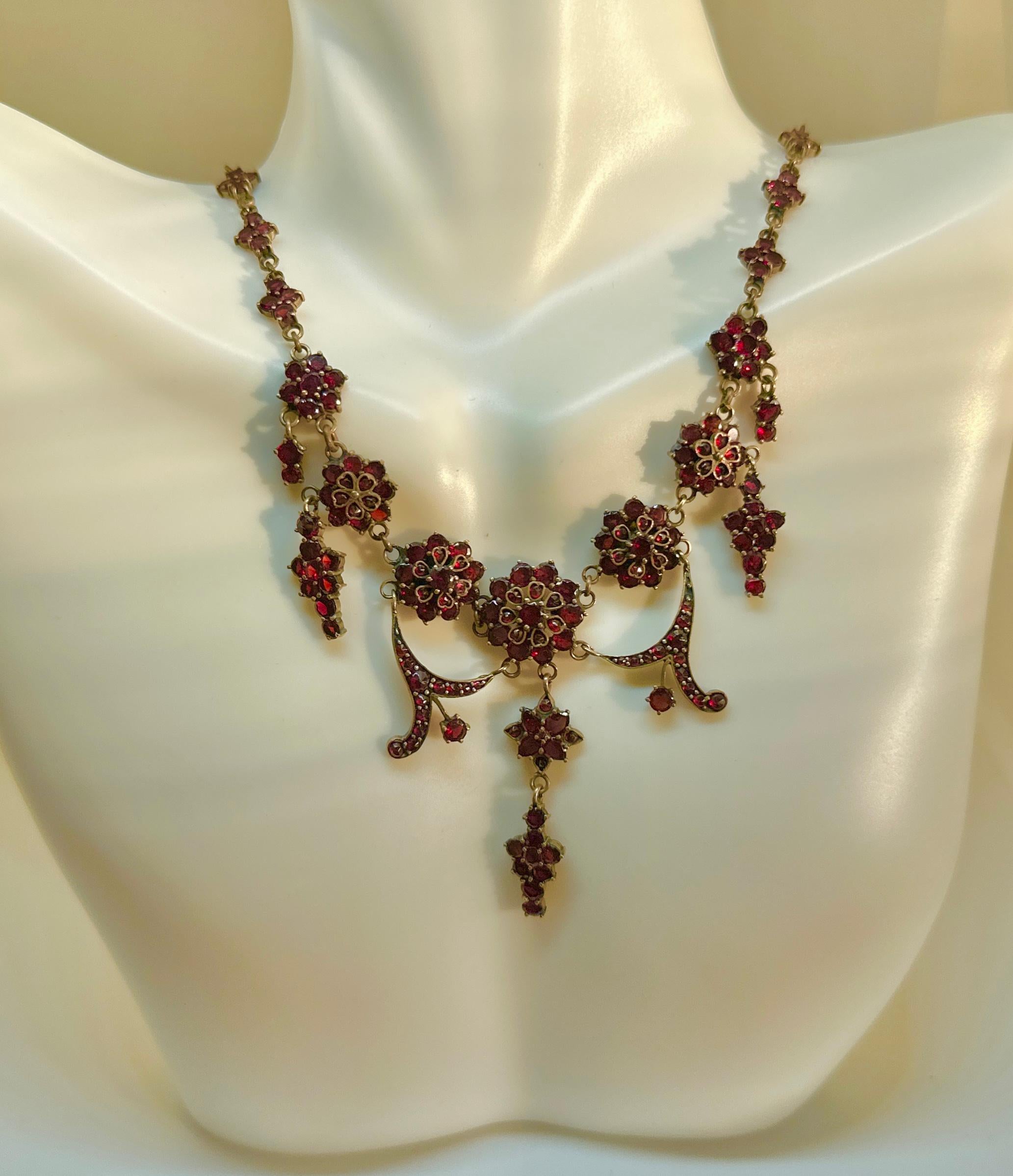 Indulge in a gorgeous Belle Epoque - Victorian Bohemian Garnet Festoon Necklace in a heart and flower motif of great beauty. The early festoon necklace is set throughout with flat cut garnets which are indicative of the early age of the necklace.