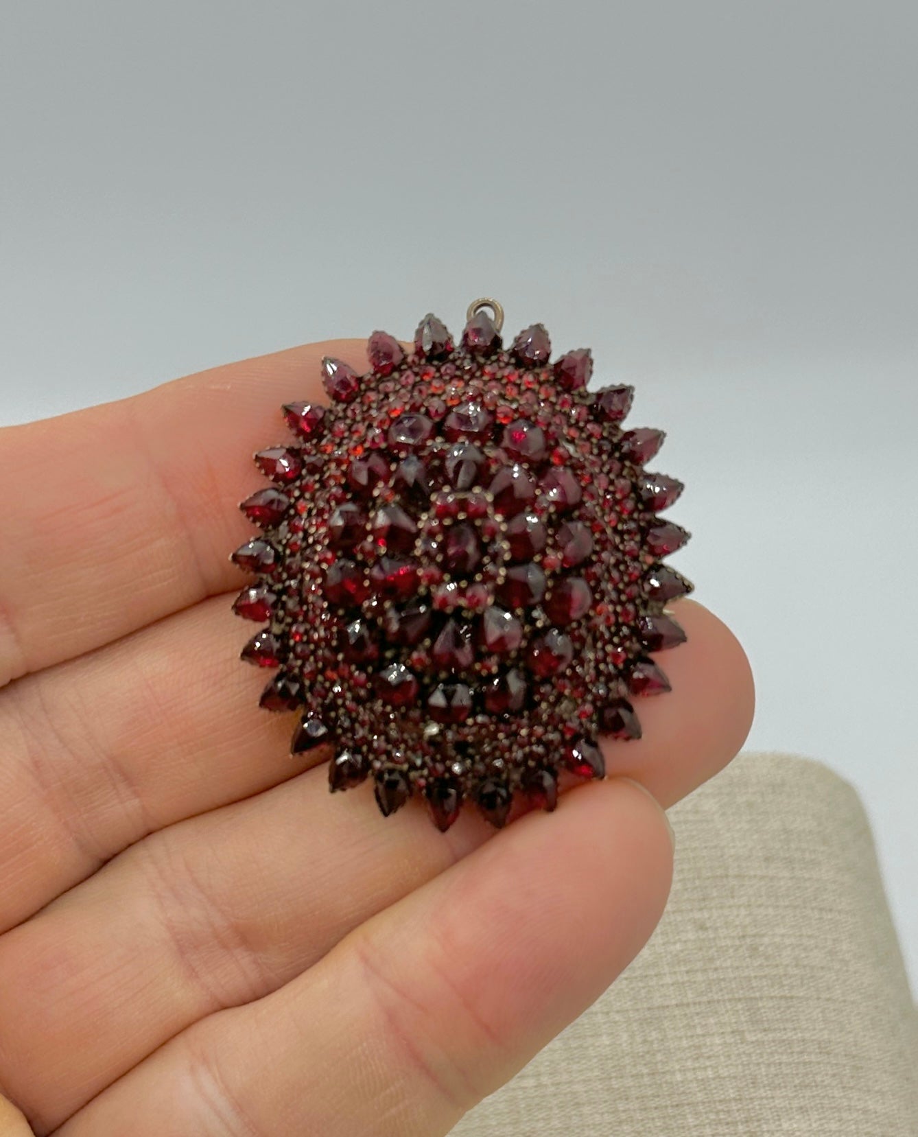 This is a gorgeous Belle Epoque - Victorian Bohemian Garnet Locket Pendant or Brooch.  The early oval locket pendant is adorned with four layers of faceted garnets.  The garnets are pear shape and round and are of absolutely magnificent blood red