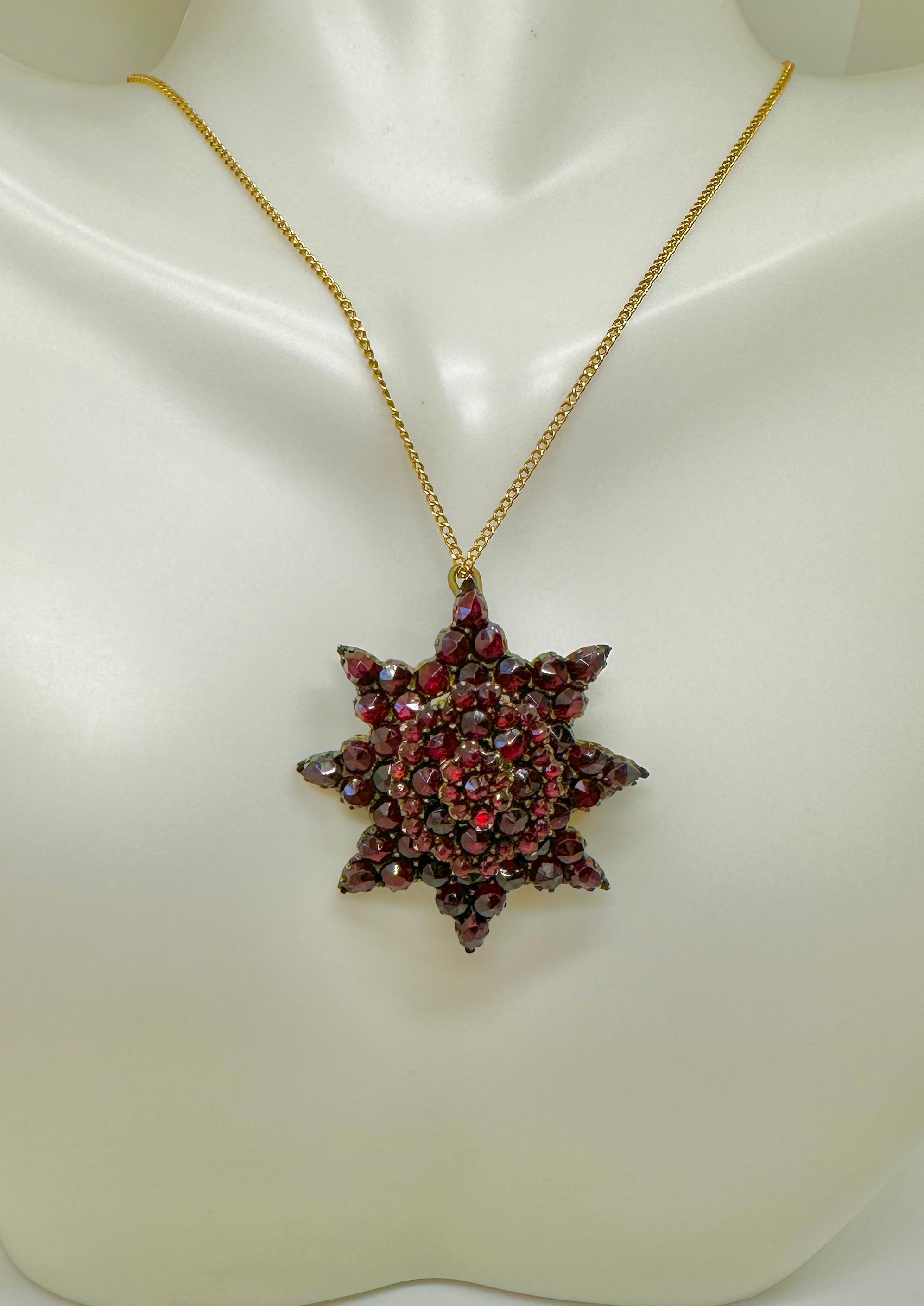 This is a gorgeous Belle Epoque - Victorian Bohemian Garnet Locket Pendant or Brooch in a stunning star motif.  The early oval locket pendant is adorned with three layers of faceted garnets.  The garnets are pear shape and round and are of