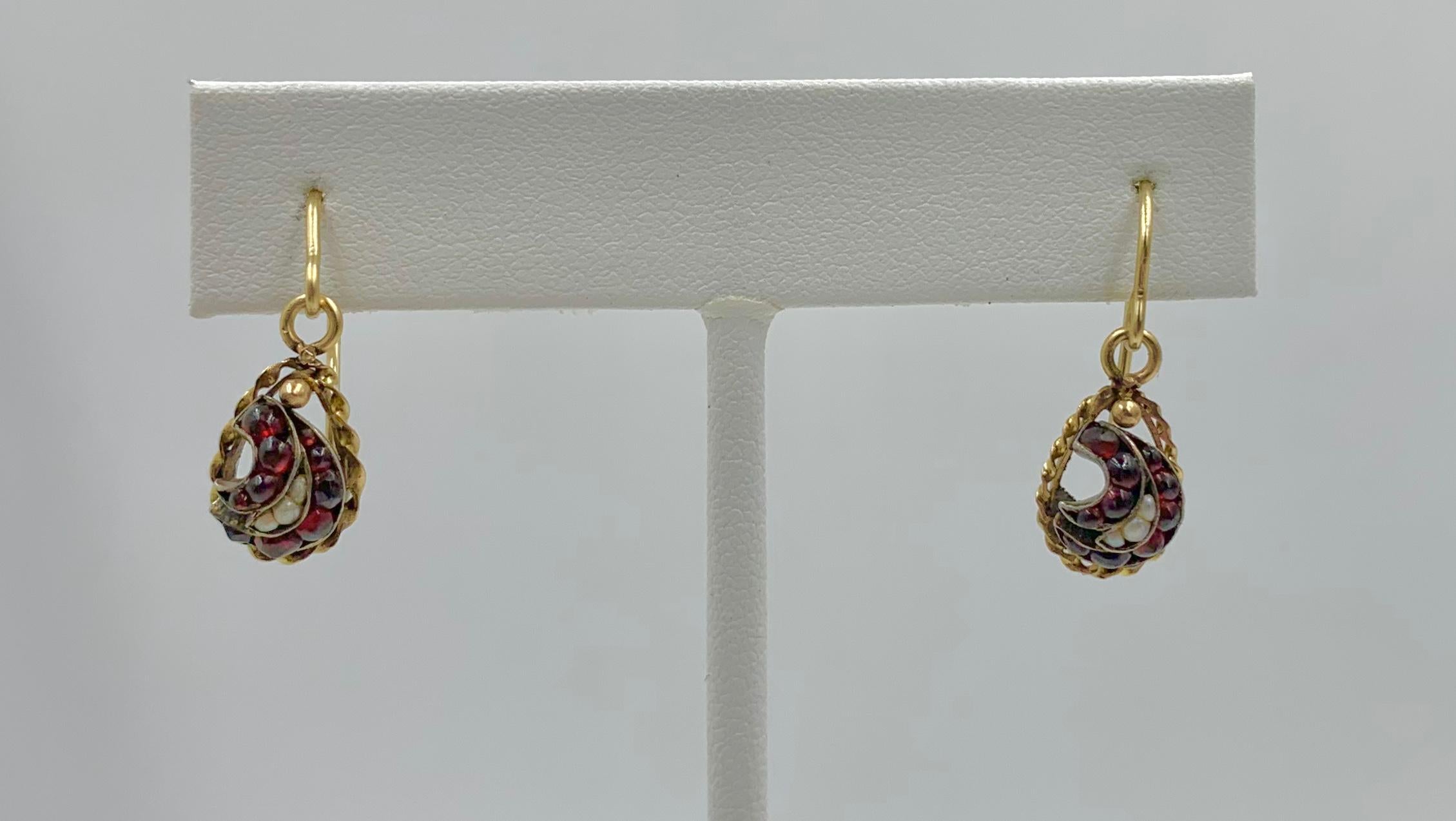 Dies ist ein seltenes Paar viktorianischer böhmischer Granat- und Perlentropfen-Ohrringe aus 10 Karat Gold.  Die exquisiten Ohrringe haben ein Wirbelmotiv, das mit wunderschönen böhmischen Granat-Cabochons und Perlenakzenten besetzt ist.  Die