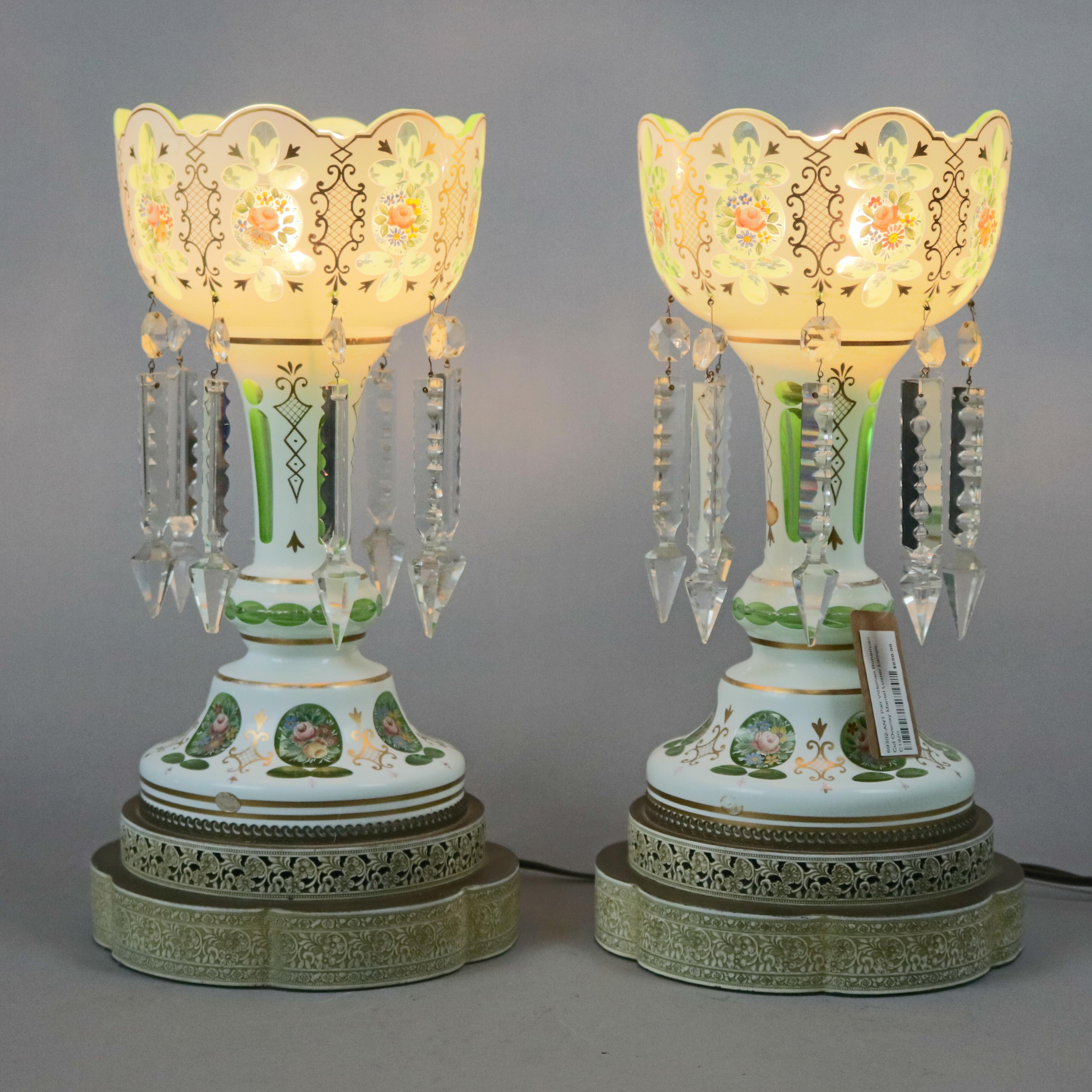A pair of Bohemian glass mantel luster lamps offer white to emerald green cut overlay glass with bowl having scalloped rim, hanging cut crystal prisms, floral hand painted reserves and gilt decoration throughout, seated on scroll and foliate