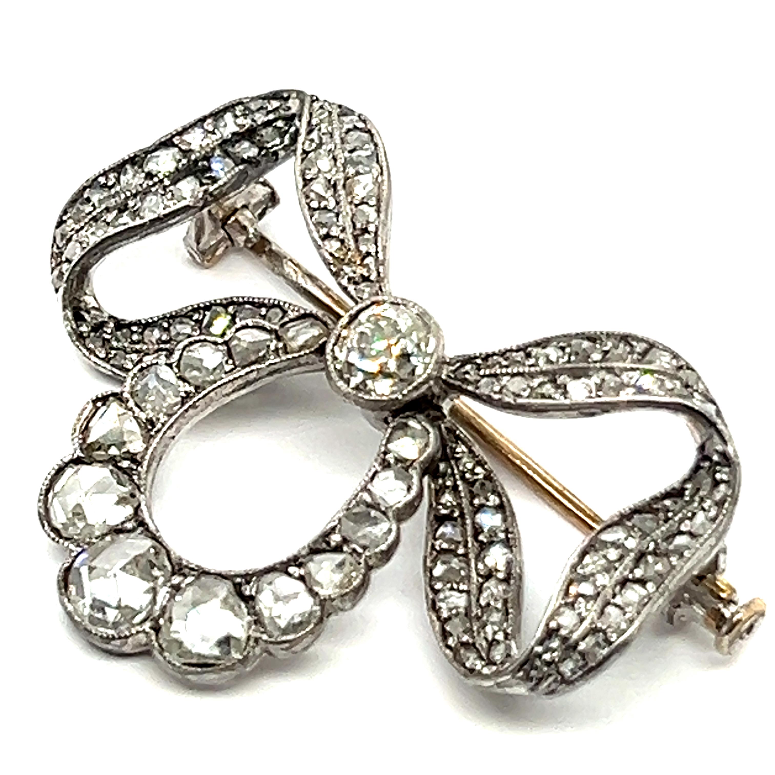 Embrace the elegance of this charming bow brooch. Reflecting the era's penchant for contrast and luxury, the combination of 18 Karat yellow gold and silver was favored for its ability to create striking visual effects. Adorned with an old and rose