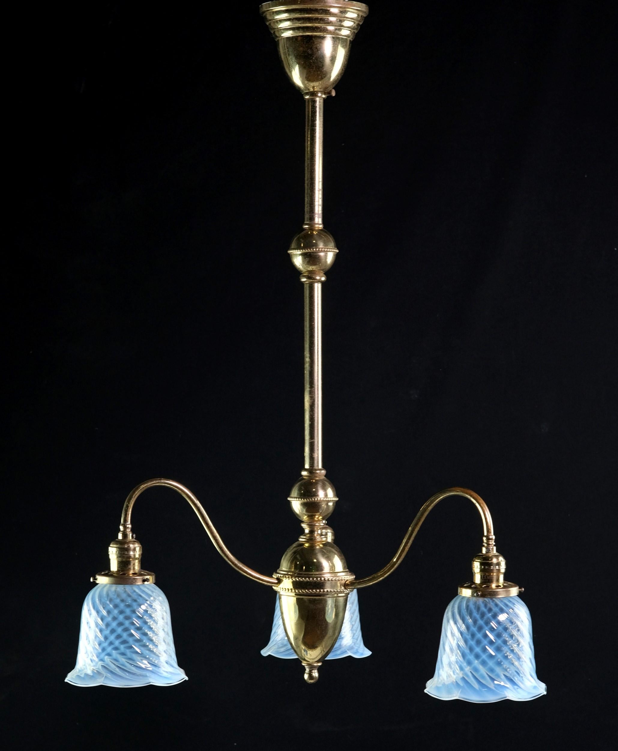 Eleganter Messingkronleuchter aus der Jahrhundertwende mit drei Down-Lights und opalisierenden, gewirbelten Glasschirmen aus Gas. Diese Pendelleuchte hat einen Baldachin, eine Stange und gebogene Arme aus Messing mit einer warmen, natürlichen
