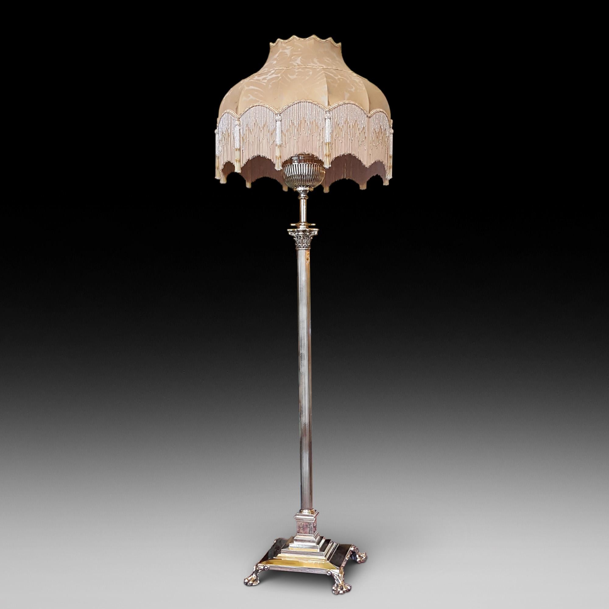 Brass telescopic standard lamp, with reeded oil lamp converted for electricity, on extending shaft, in turn above a Corinthian capital on reeded column and square stepped base with lion paw and ball feet 22