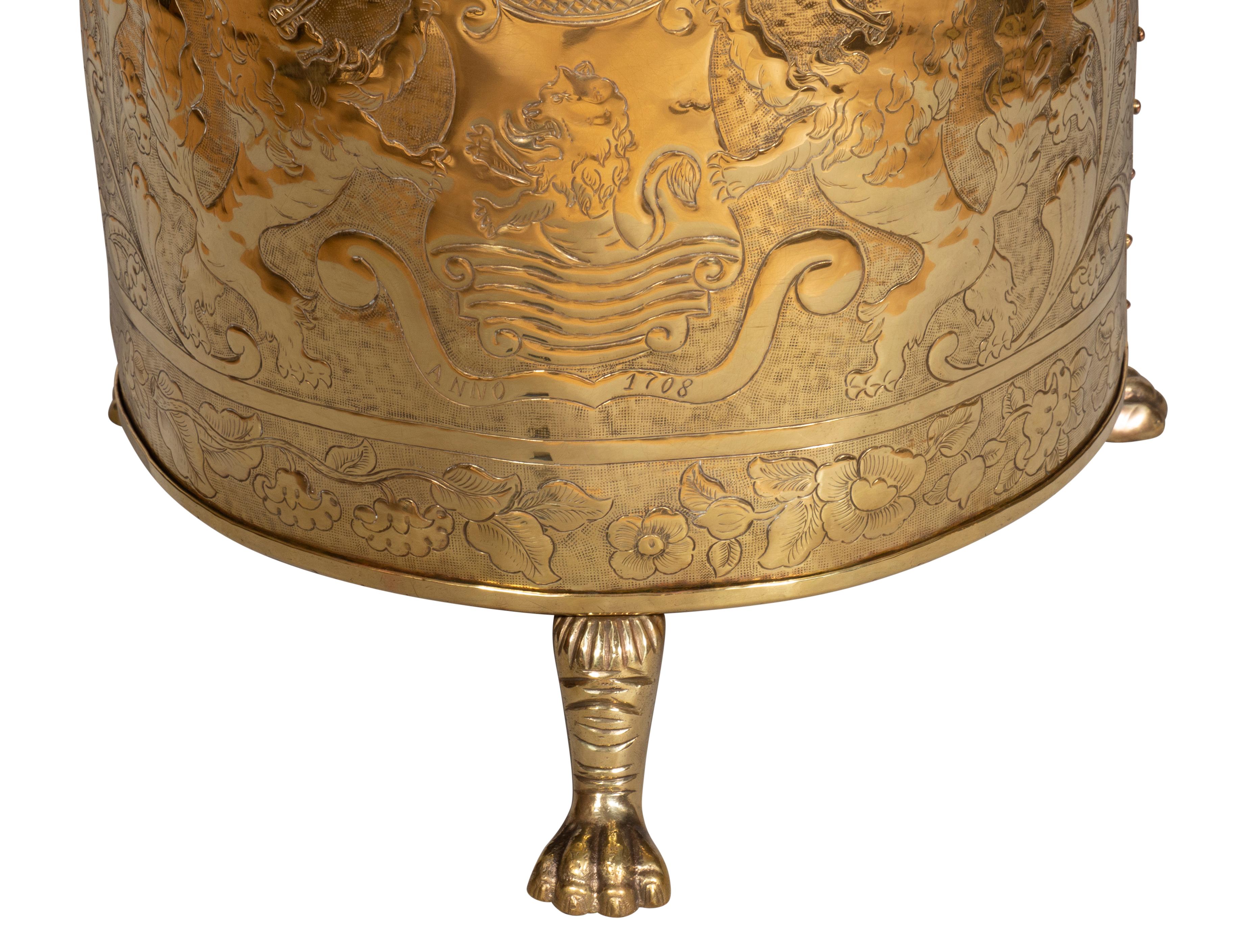 Cylindrical with lions head handles and overall rampant lion hammered decoration. Brass feet.