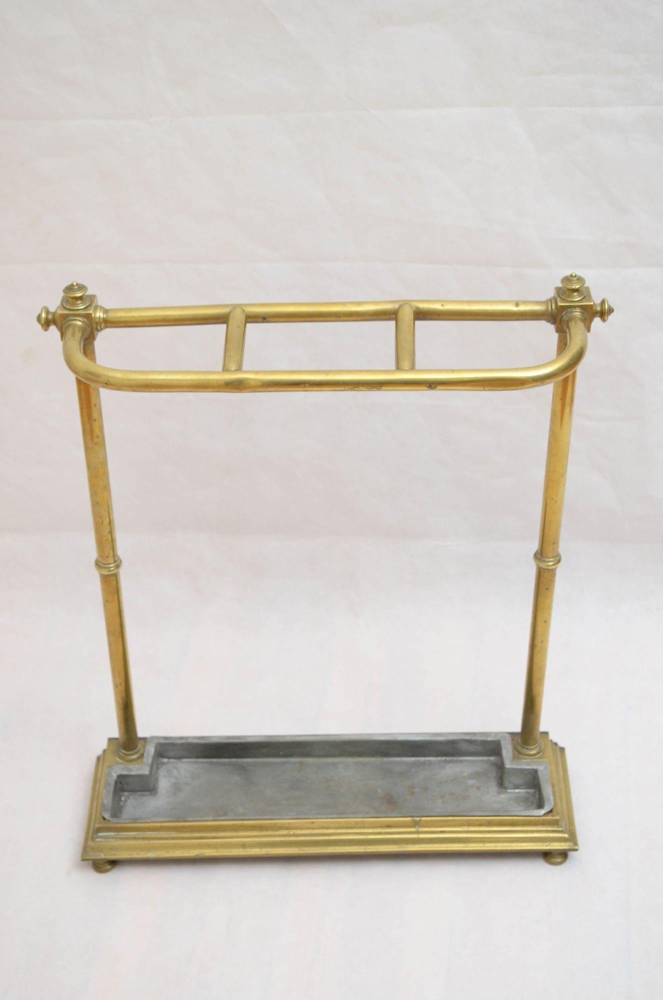 P0255A Unusual Victorian umbrella stand in brass having three divisions and very decorative reeded finials to the top and sides, raised on reeded uprights terminating in stepped base with removable drip tray, all standing on bun feet. This antique