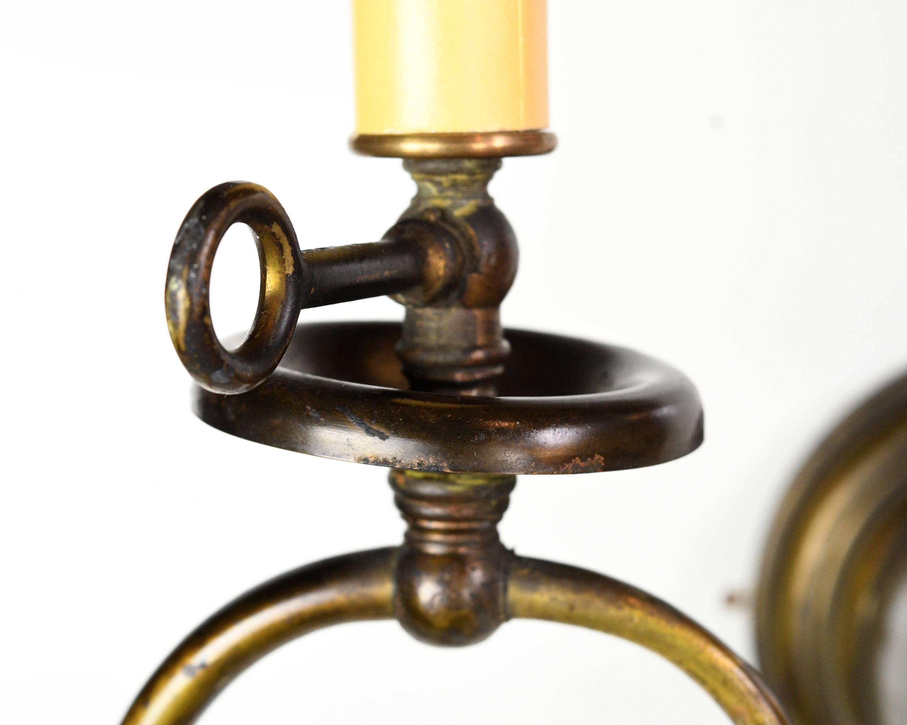 A very special brass sconce combining two types of lights. On one end there’s the candle light while the other end is a electric light with beautiful glass shade. While the light is asymmetrical, the visual weight is well balanced. The design
