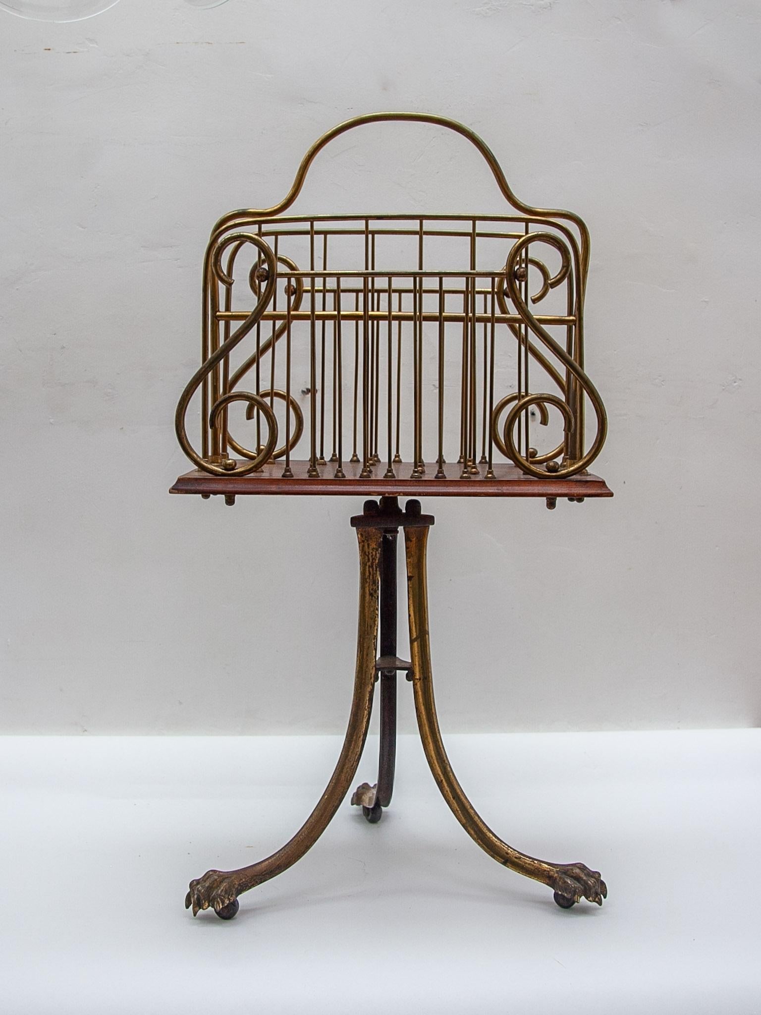 Quality Antique Victorian brass and mahogany revolving magazine stand having a shaped brass handle to the centre, four sections for magazines with brass mesh wire on a mahogany revolving base with a moulded edge and supported on three shaped brass