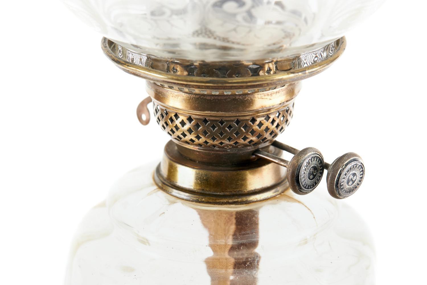 19th Century Victorian antique brass oil lamp of good quality having an etched glass shade above a quality clear glass brass reservoir supported by a brass column and standing on a circular black pottery base.