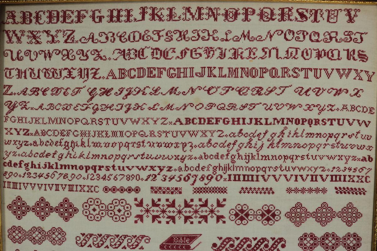1879 Bristol Orphanage sampler by M Mountain. The sampler is worked in red thread on linen ground. Multiple alphabets A-Z in upper case and lower case, in a variety of fonts. Numbers 0-9 and roman numerals. Signed and dated 'M Mountain No.5 Orphan
