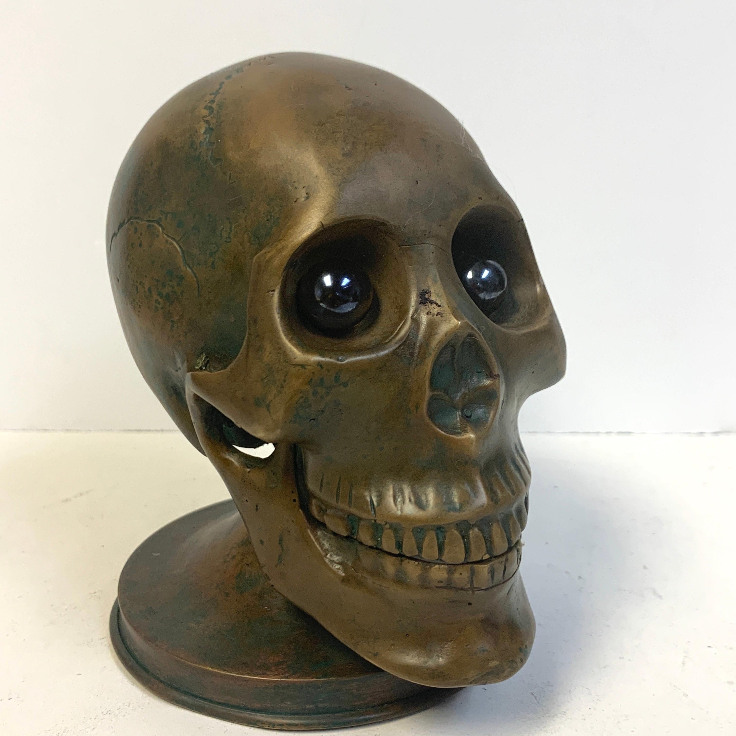 Victorian bronze skull with glass eyes, by S.W. Farber, New York, realistically cast and modeled, with inset round glass eyes, raised on a 4