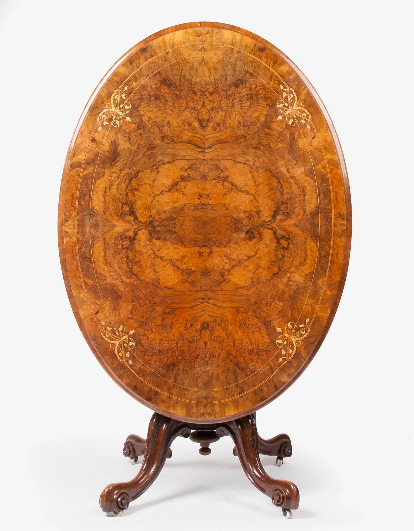 Oval table with a till-top. 
The top is veneered with walnut-burl and decorated with fine marquetry. 
The foot is made from mahogany, it is solid and carved.
The till-top mechanism is working well. 
This table is resting on 4 feet, so it is