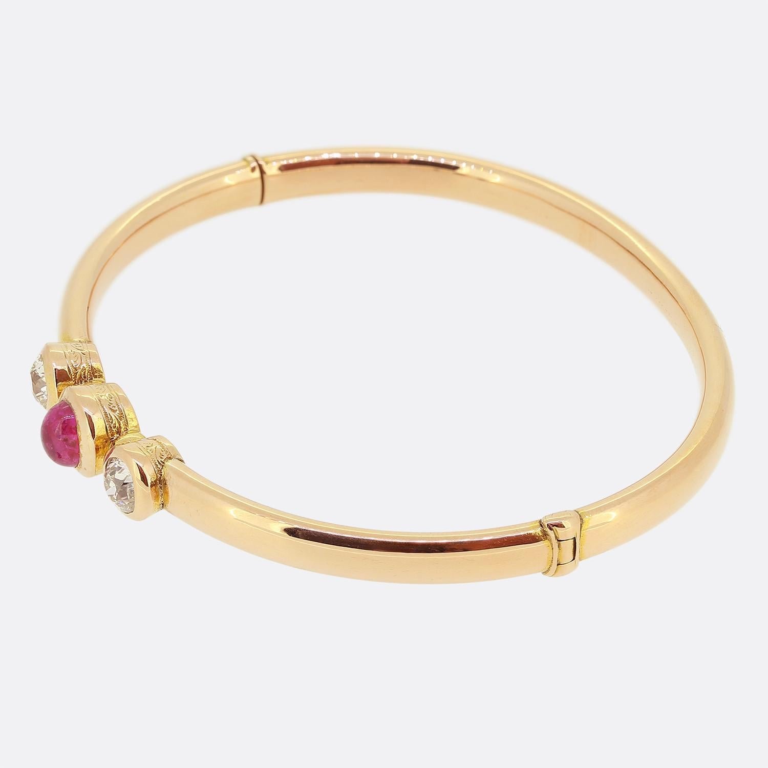 Aquí tenemos un elegante brazalete tomado que data de la época victoriana. Esta pieza antigua se ha elaborado en oro rosa de 18 ct con una banda pulida lisa que alberga un trío de piedras preciosas en la cara. En el centro encontramos un único rubí