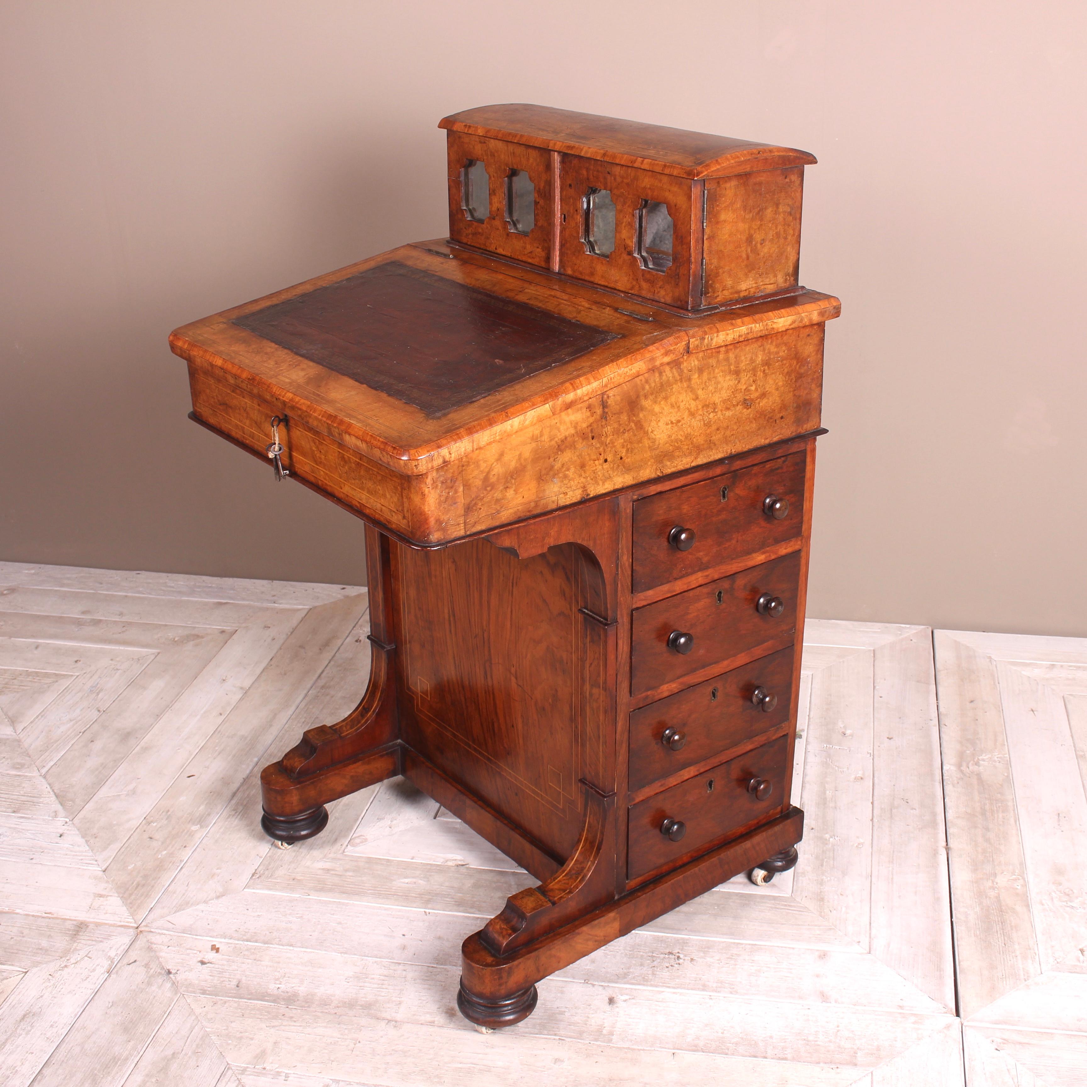 An attractive Victorian burr walnut Davenport. Having an unusual domed and mirrored upper section housing two drawers, one being split into sections with pen tray, flanked by cubby holes. The inset leather writing slope enclosing two further drawers
