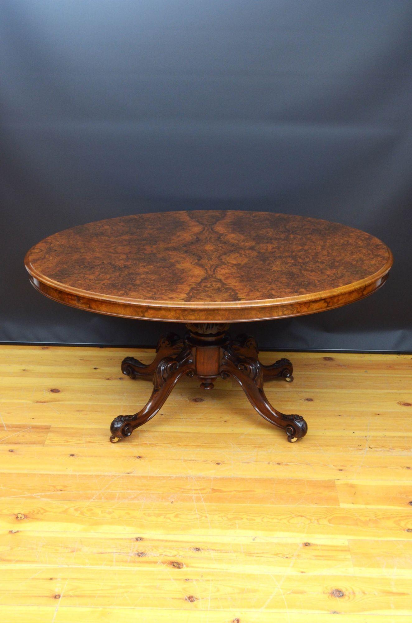 R037 Fine quality Victorian burr walnut dining table or centre table, having an oval top with outstanding walnut drain and moulded edge, raised on leaf carved vase shaped column terminating in four carved cabriole legs, all standing on castors. This