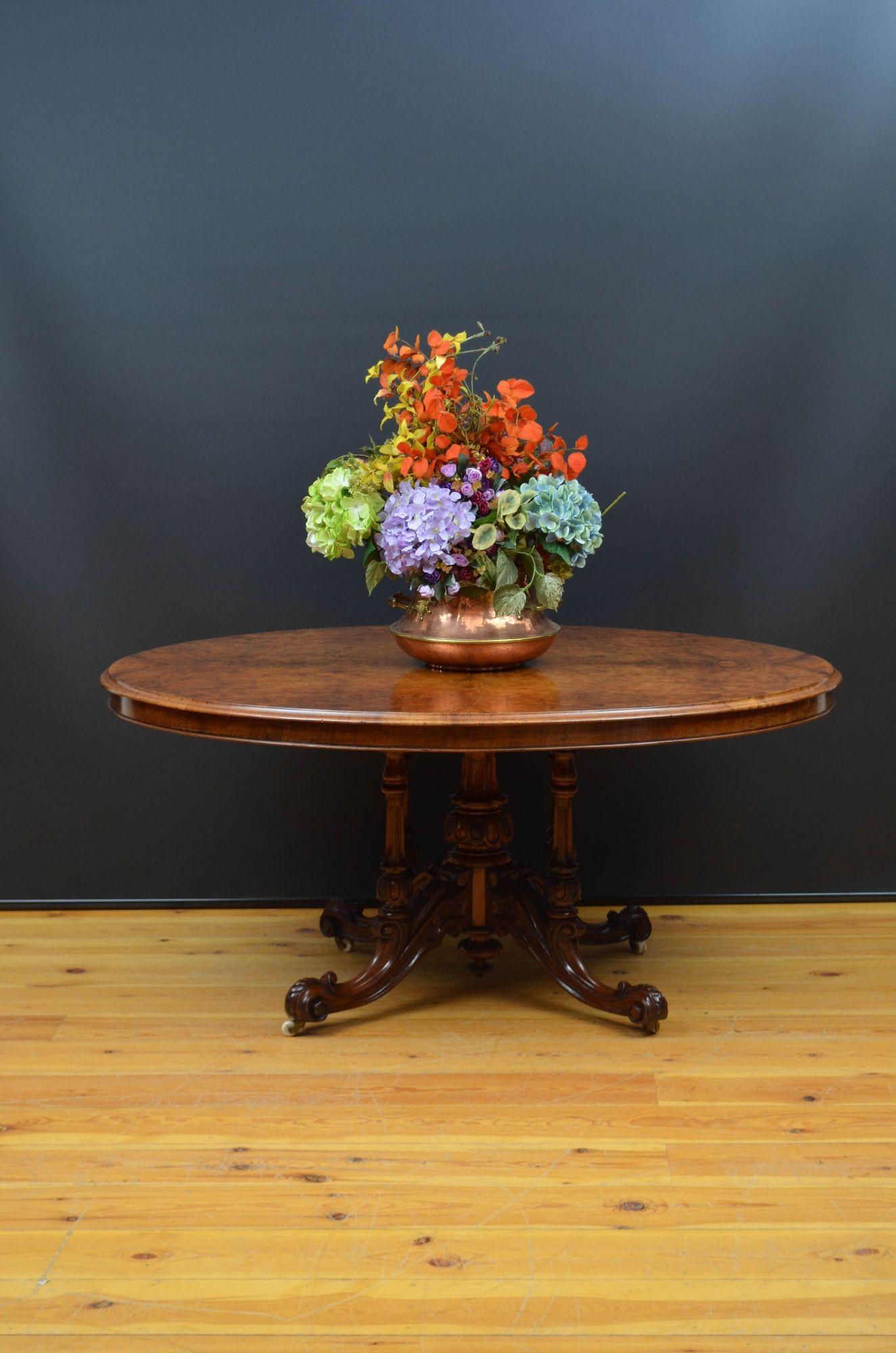 Sn5575 Fine quality Victorian burr walnut centre table, having an oval top with outstanding walnut grain and moulded edge above a shallow frieze, raised on petal carved vase shaped column with four finely carved uprights terminating in four scroll