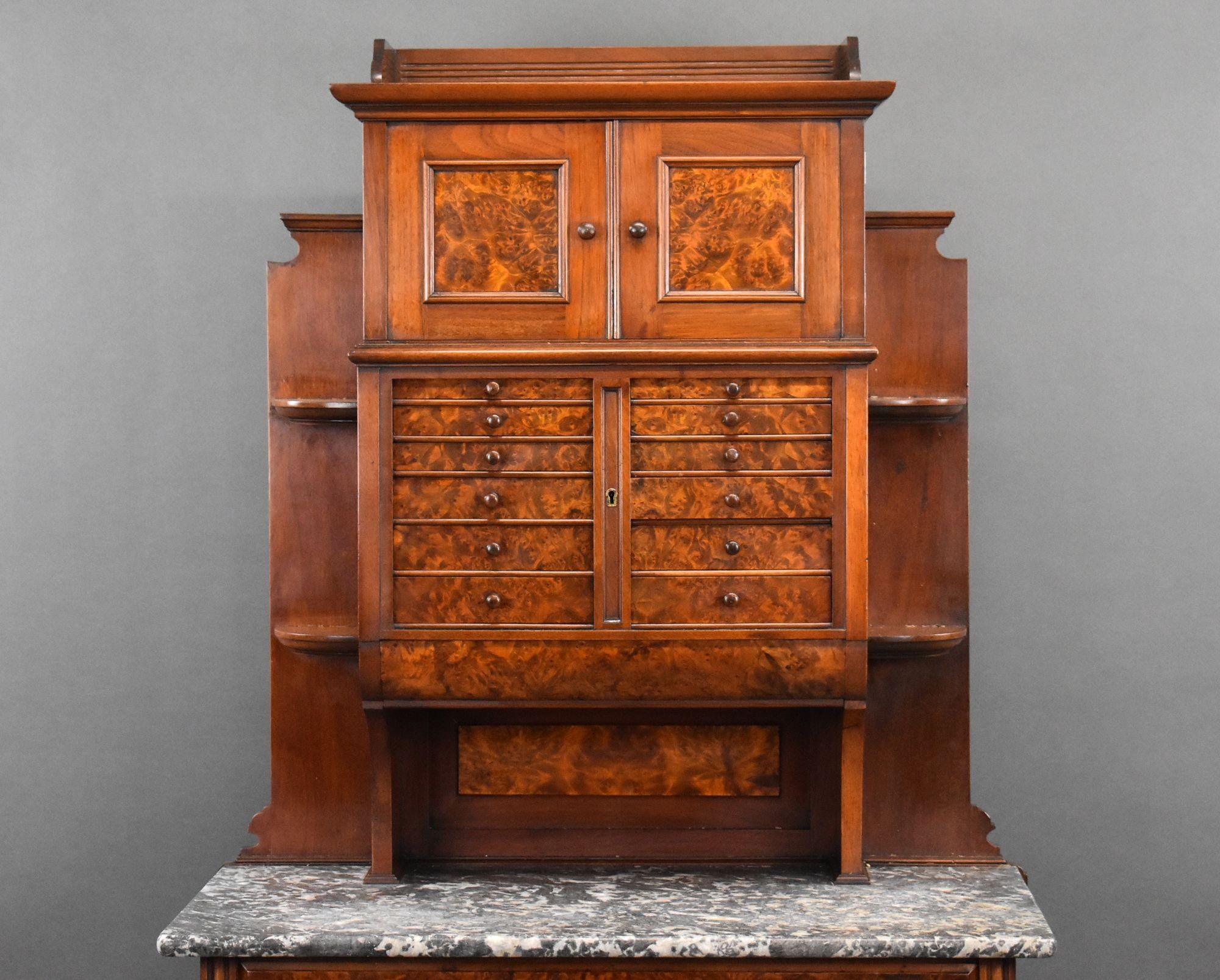For sale is a good quality Victorian burr walnut dentist cabinet, having a cupboard to the top, above an arrangement of 12 drawers, the bottom of the cupboard has a further four drawers, with two faux drawers opening as a cupboard, standing on bun