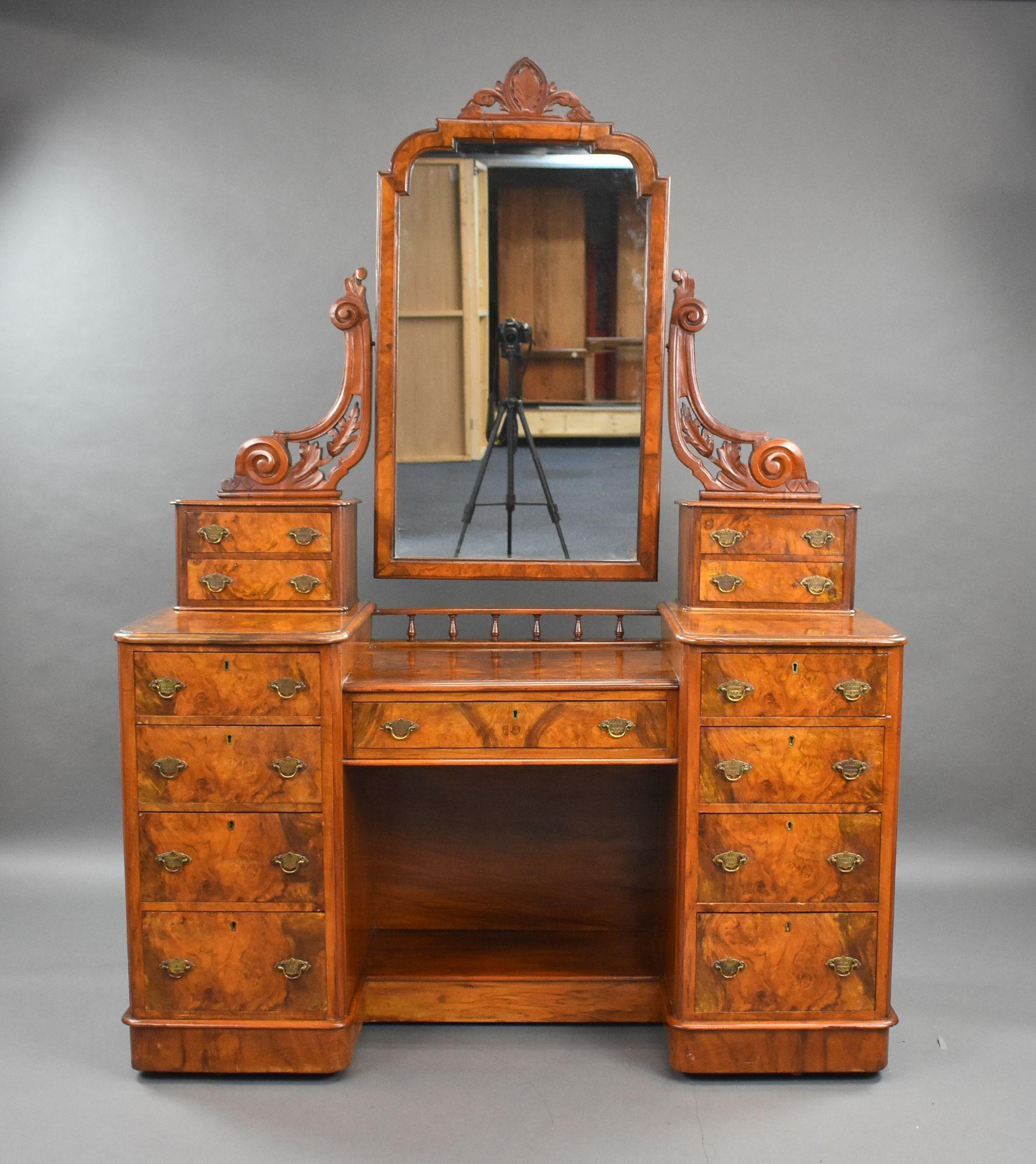 For sale is a good quality Victorian burr walnut dressing table, having a central mirror with elaborately carved supports, having two sets of small drawers above a further four graduated drawers on either side, above a plinth base. The dressing