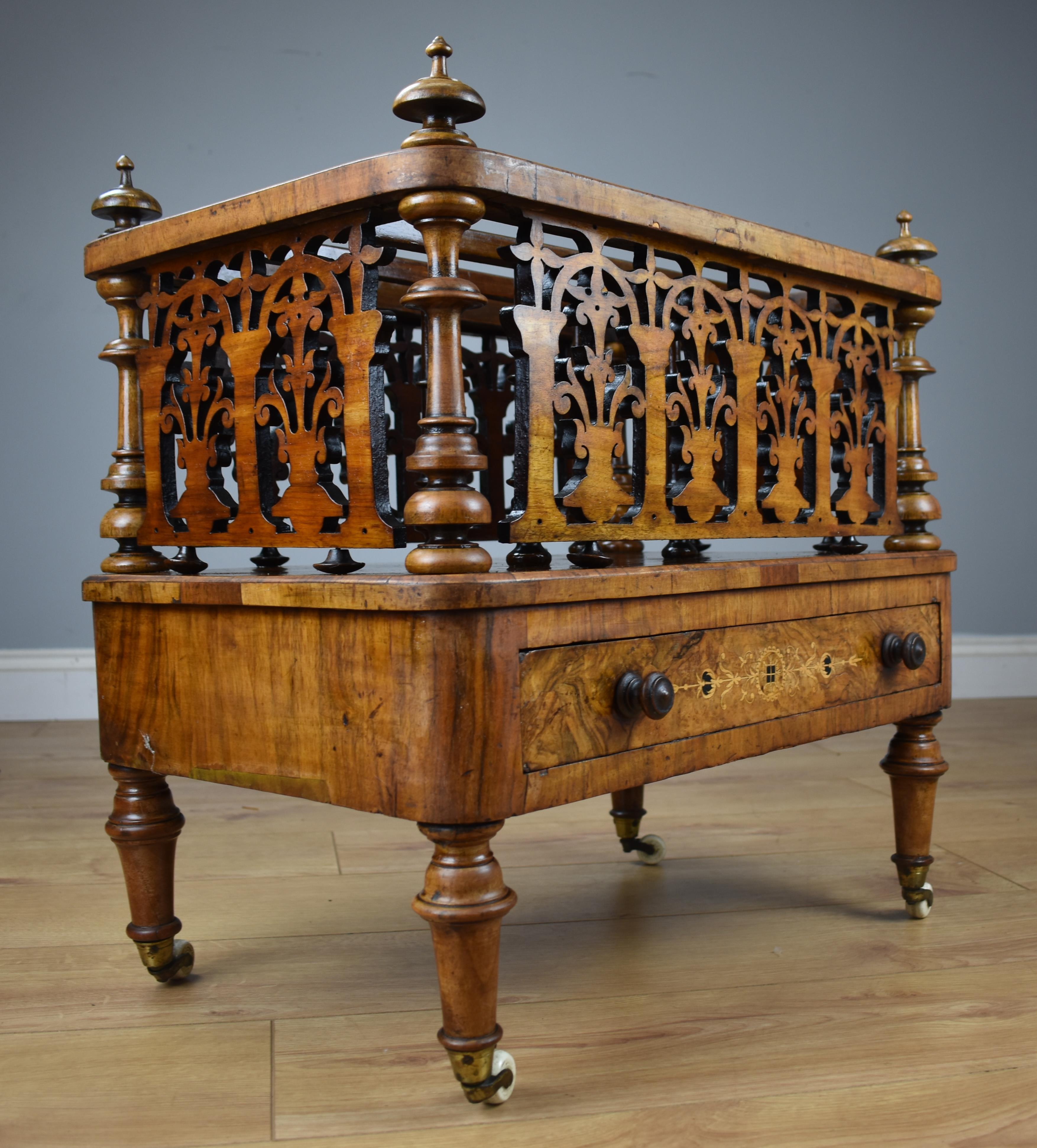 For sale is a good quality Victorian Burr walnut inlaid Canterbury with decorative pierced fretwork scroll to each side, with two partitions and decorative inlay to the top, with inlaid drawer below standing on turned legs on brass and ceramic
